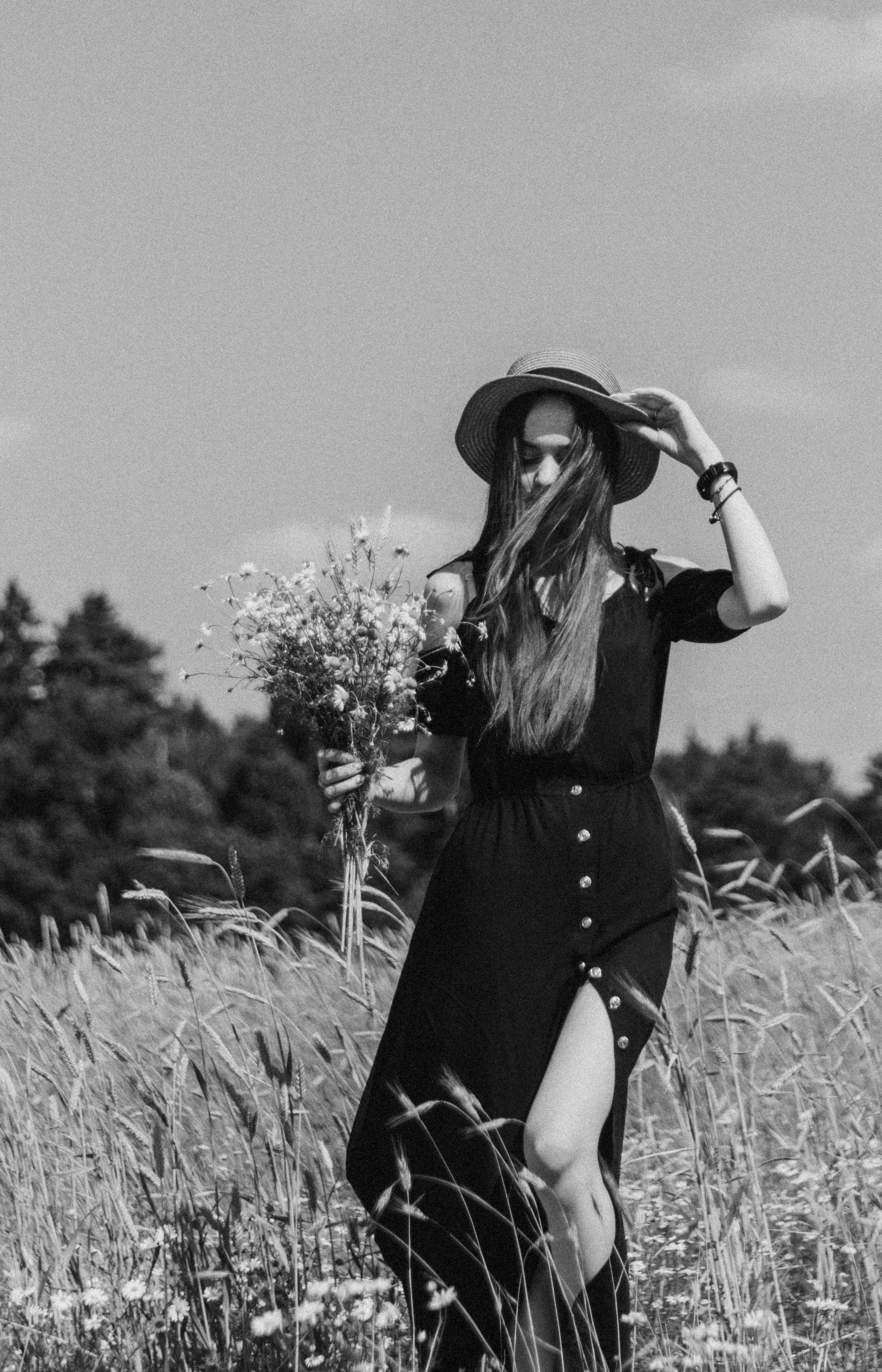 Черно белый портрет девушки в поле с букетом ромашек