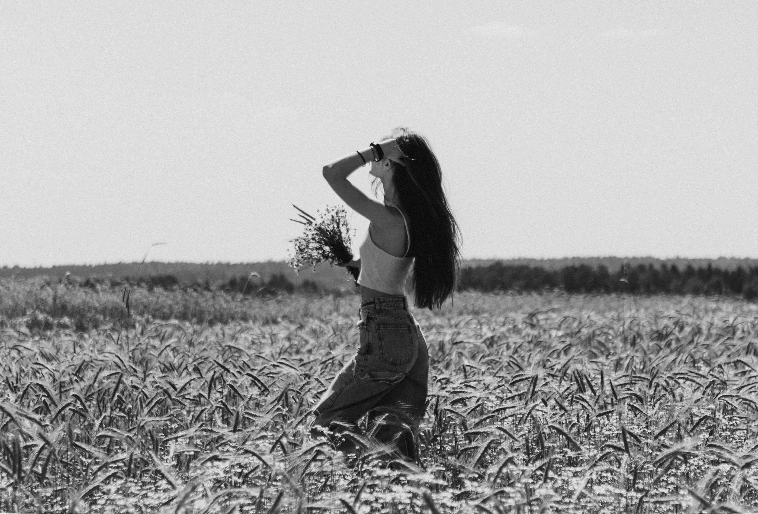 Черно белый портрет девушки в поле с букетом ромашек