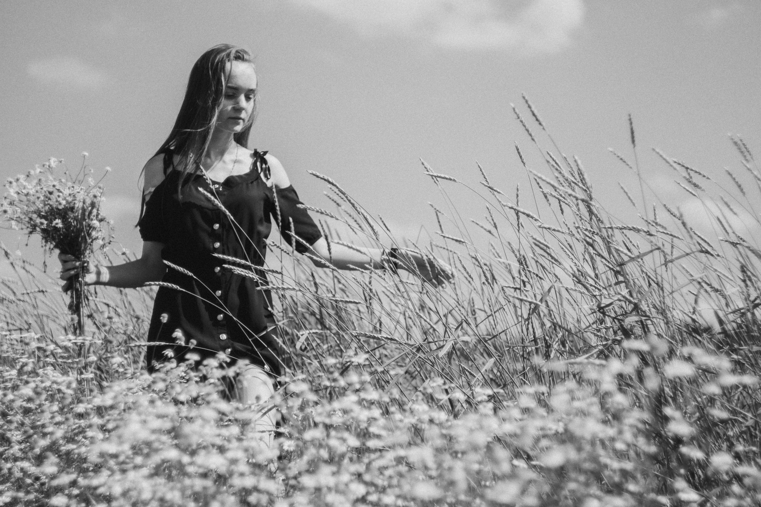 Черно белый портрет девушки в поле с букетом ромашек