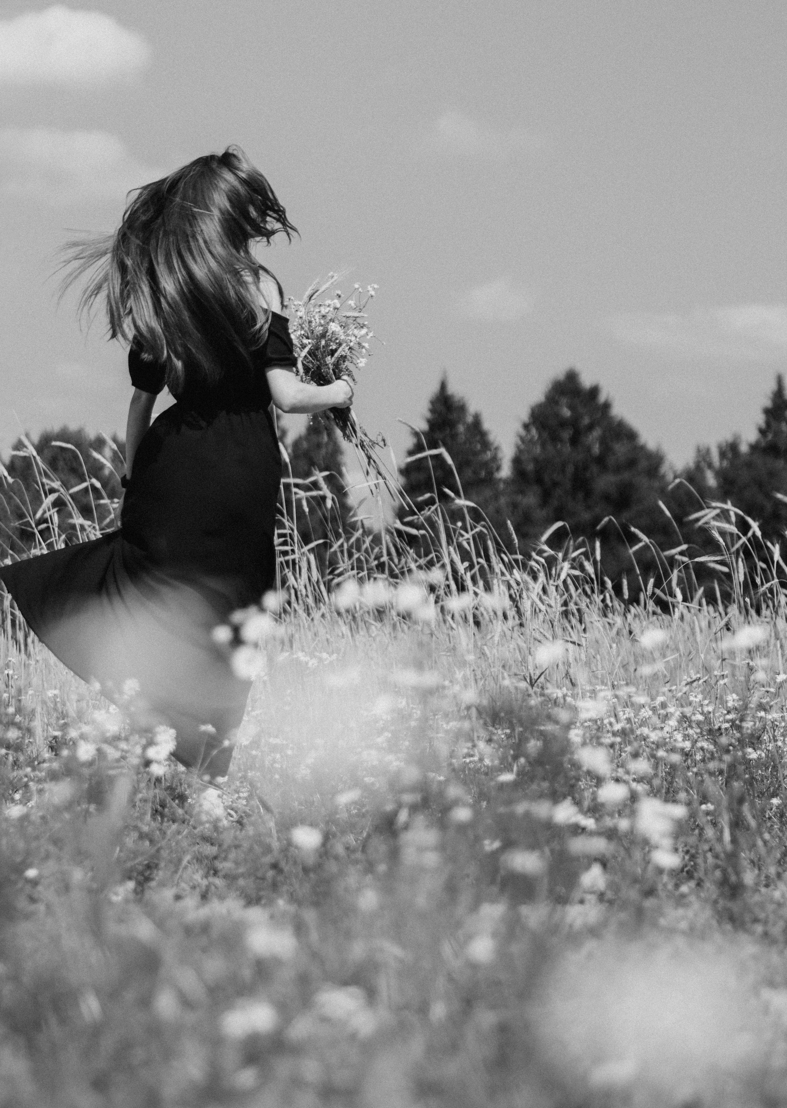 Черно белый портрет девушки в поле с букетом ромашек