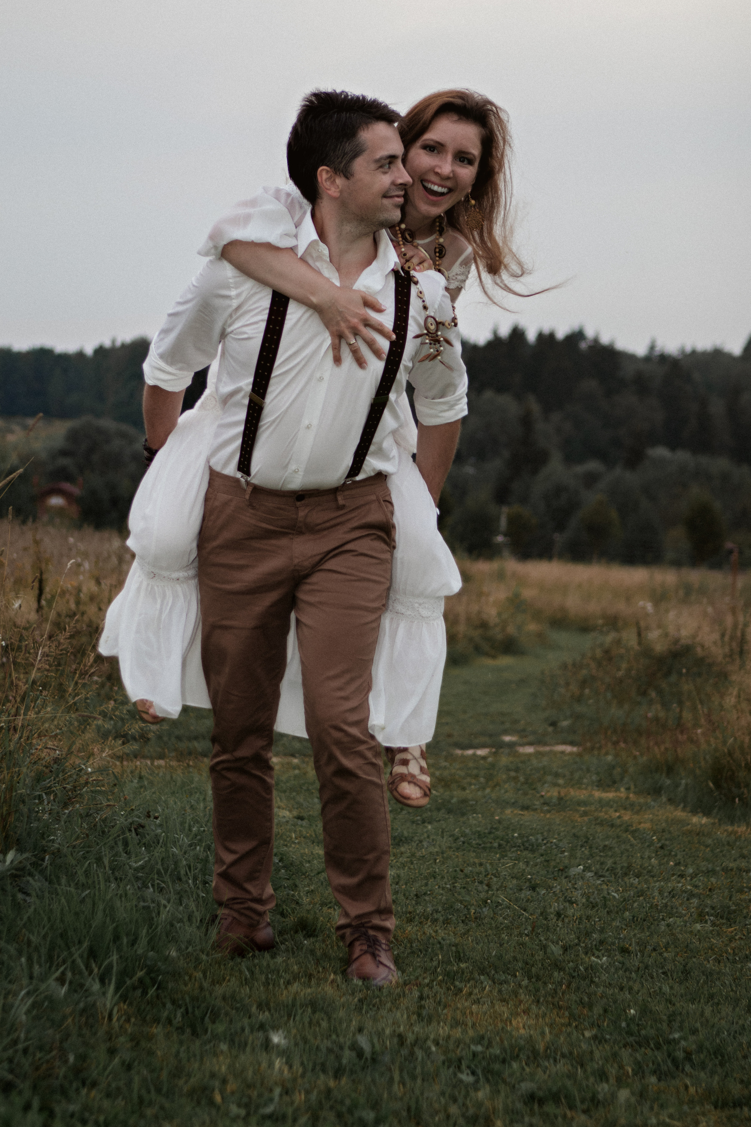 Девушка в белом на спине у мужчины в поле