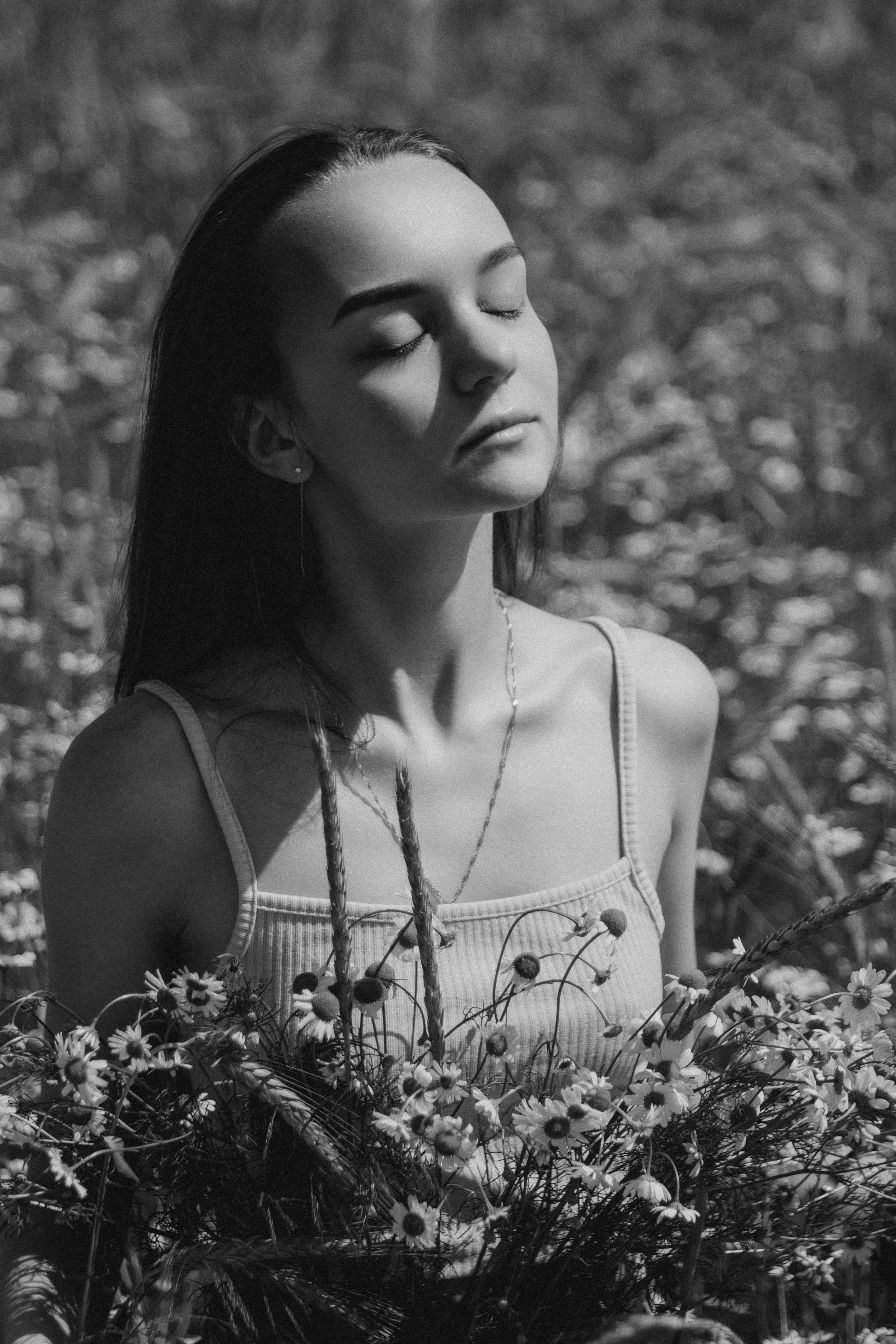 Черно белый портрет девушки в поле с букетом ромашек