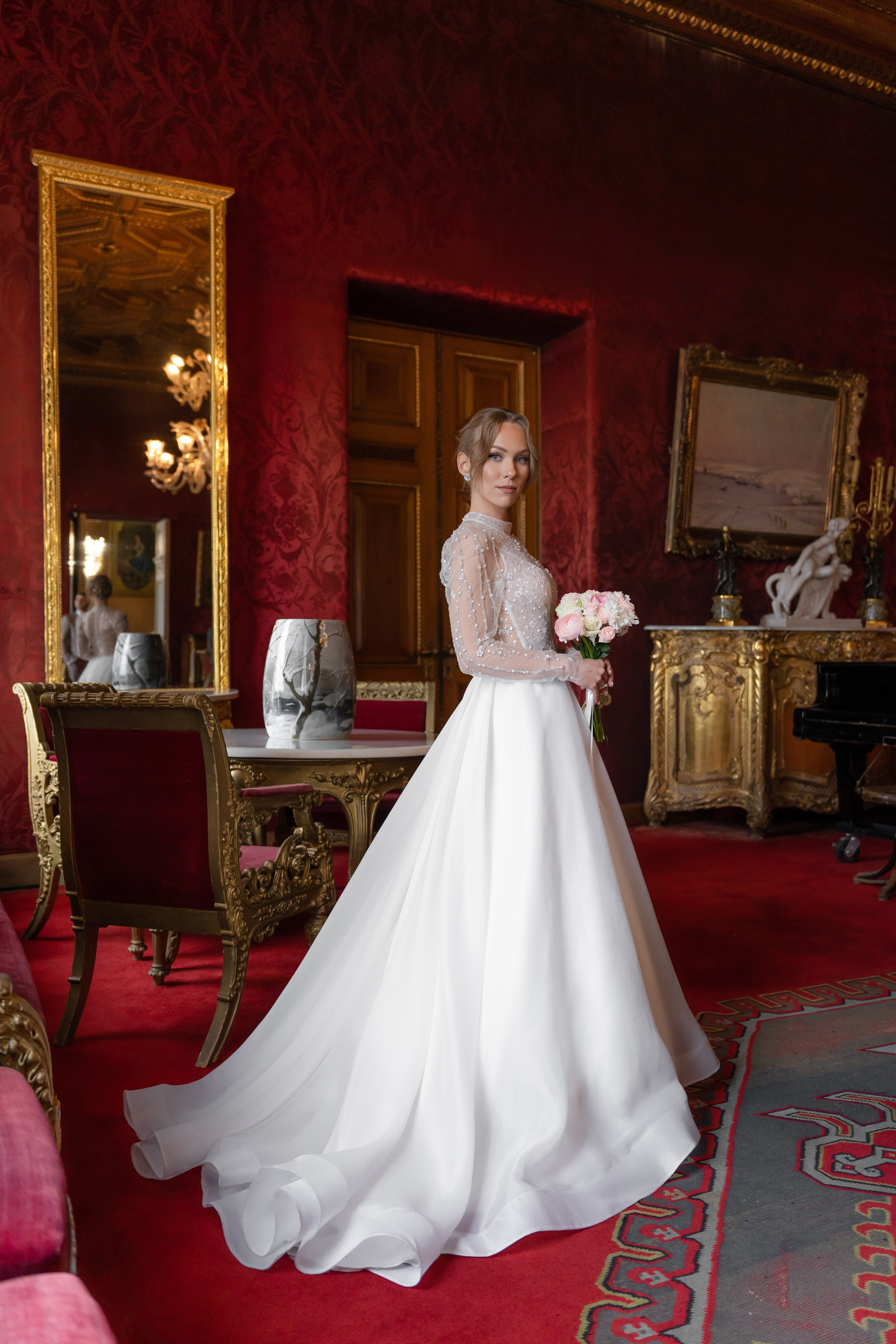 Невеста красиво стоит у окна во Дворце Великого князя Владимира в Доме учёных в Санкт-Петербурге