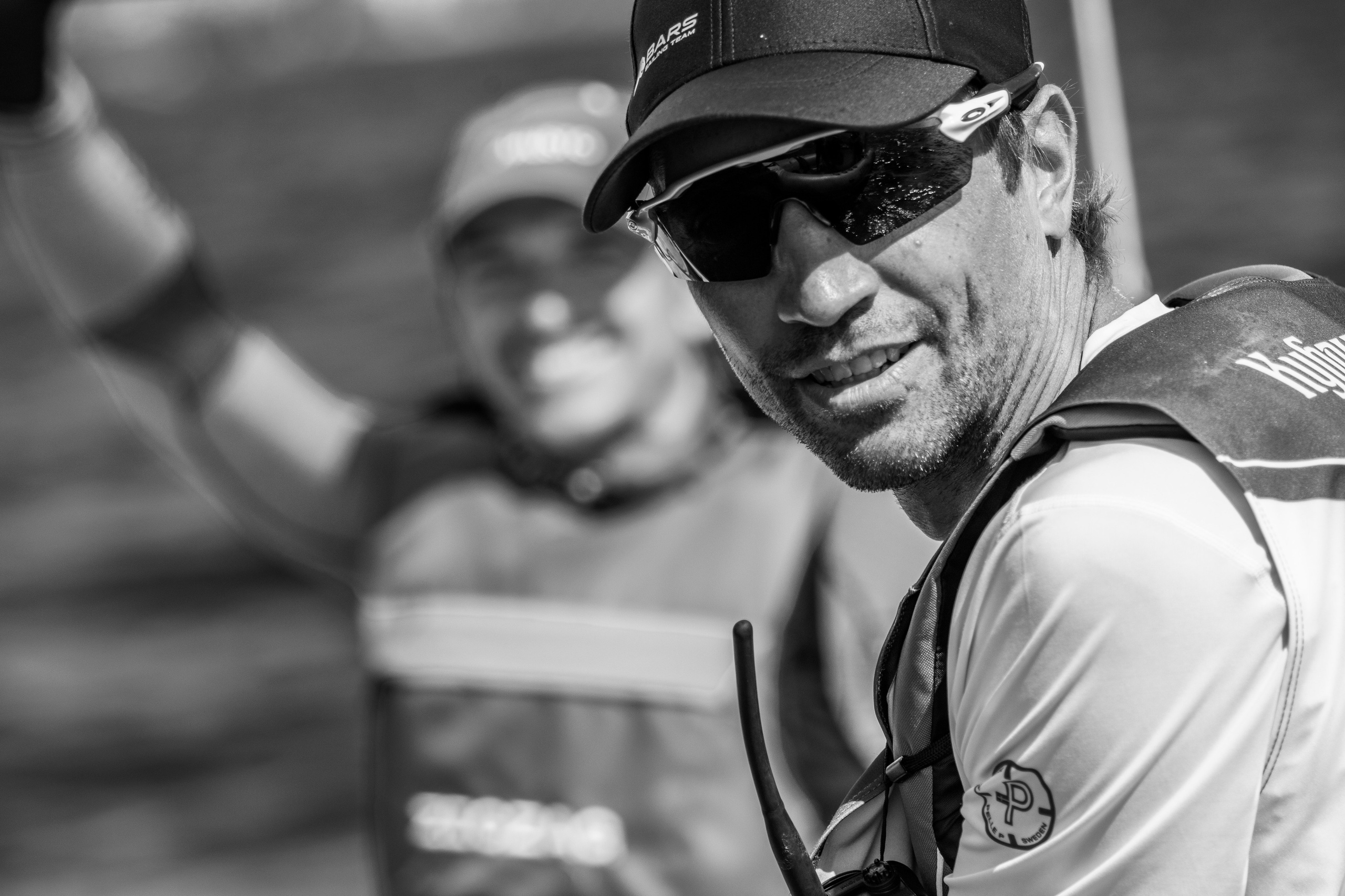 Яхтсмен на парусной регате. Черно-белый портрет в солнцезащитных очках и кепке. Красивый мужчина.