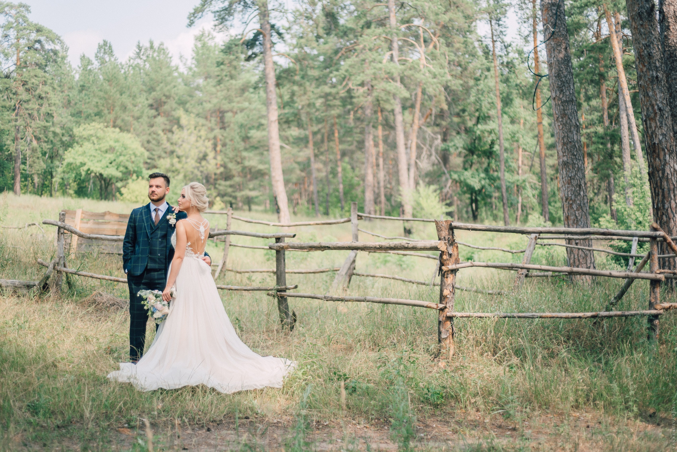 Жених и невеста возле забора в лесу