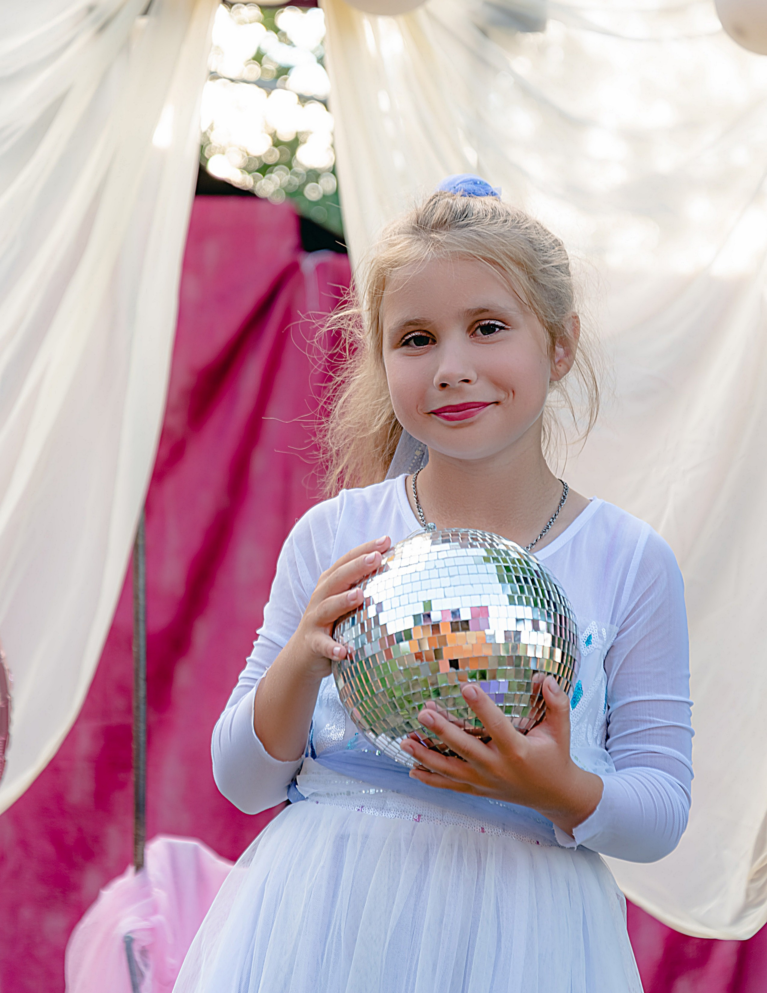 На фото девочка улыбается с шариком на день рождения.