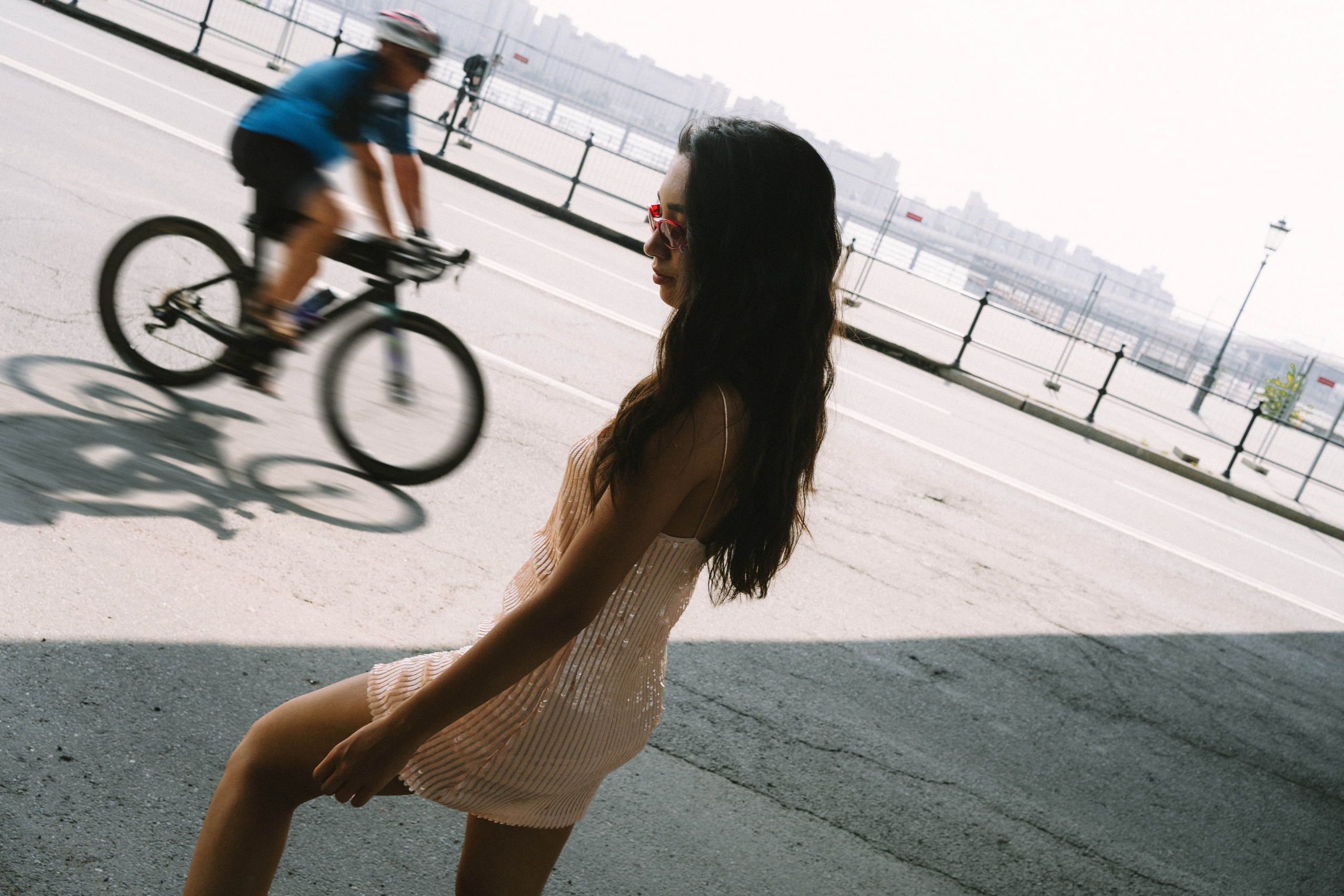 Атмосферная летняя фотография девушки в платье в тени, на фоне едет велосипед