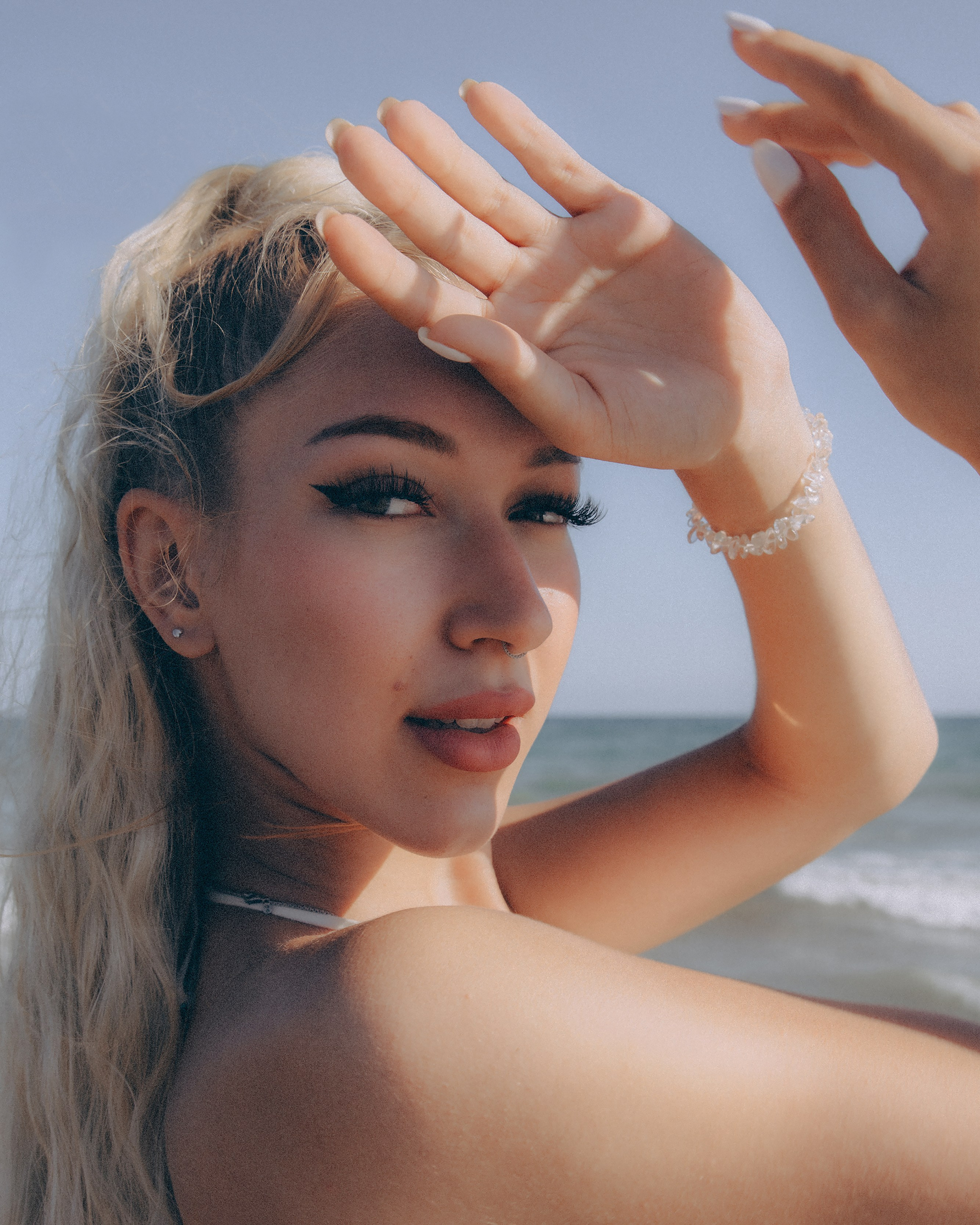 Blonde woman in elegant dress posing by the sea during a Barcelona photoshoot.