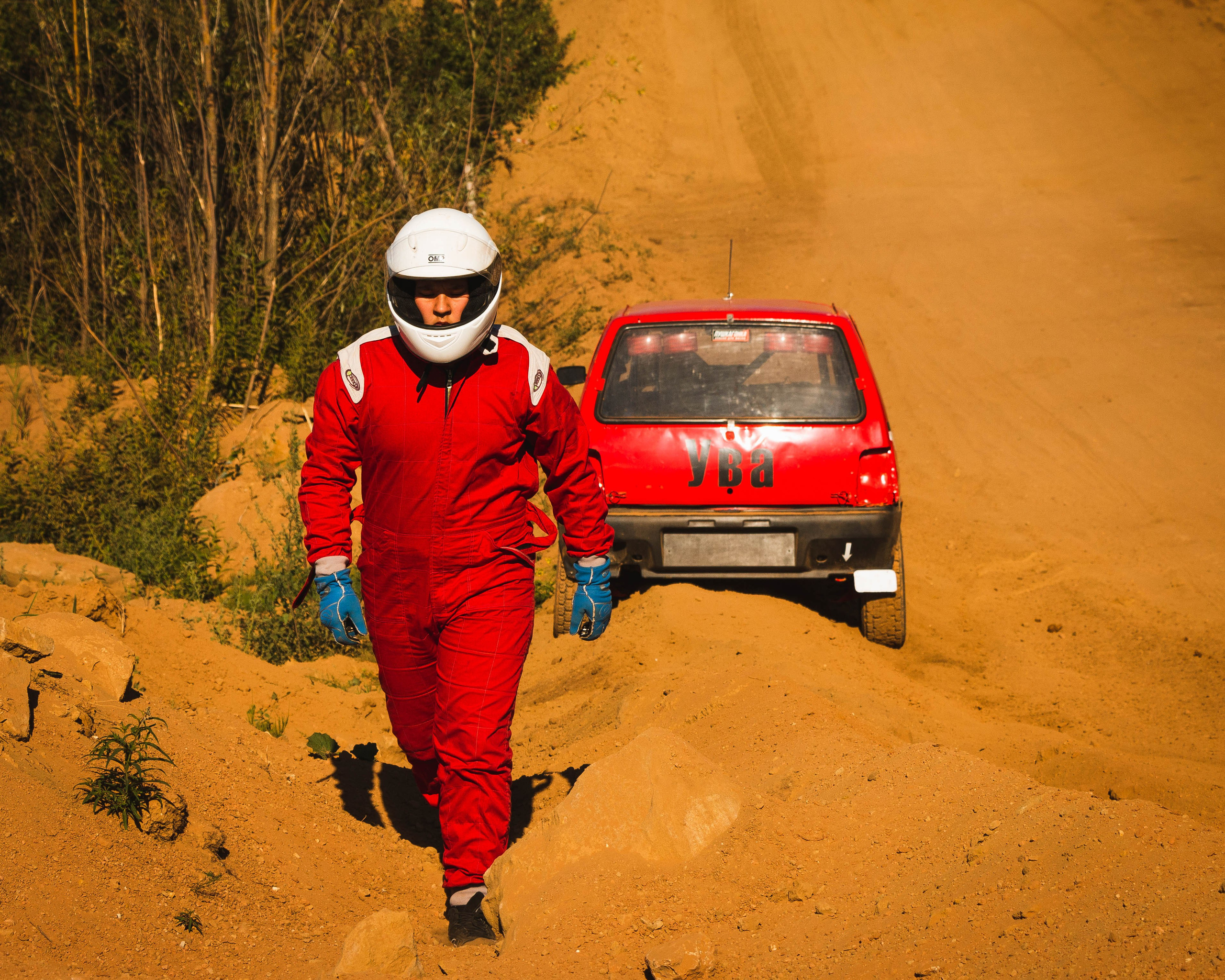 Автогонщик покидает свой автомобиль заехавший в песок на соревнованиях