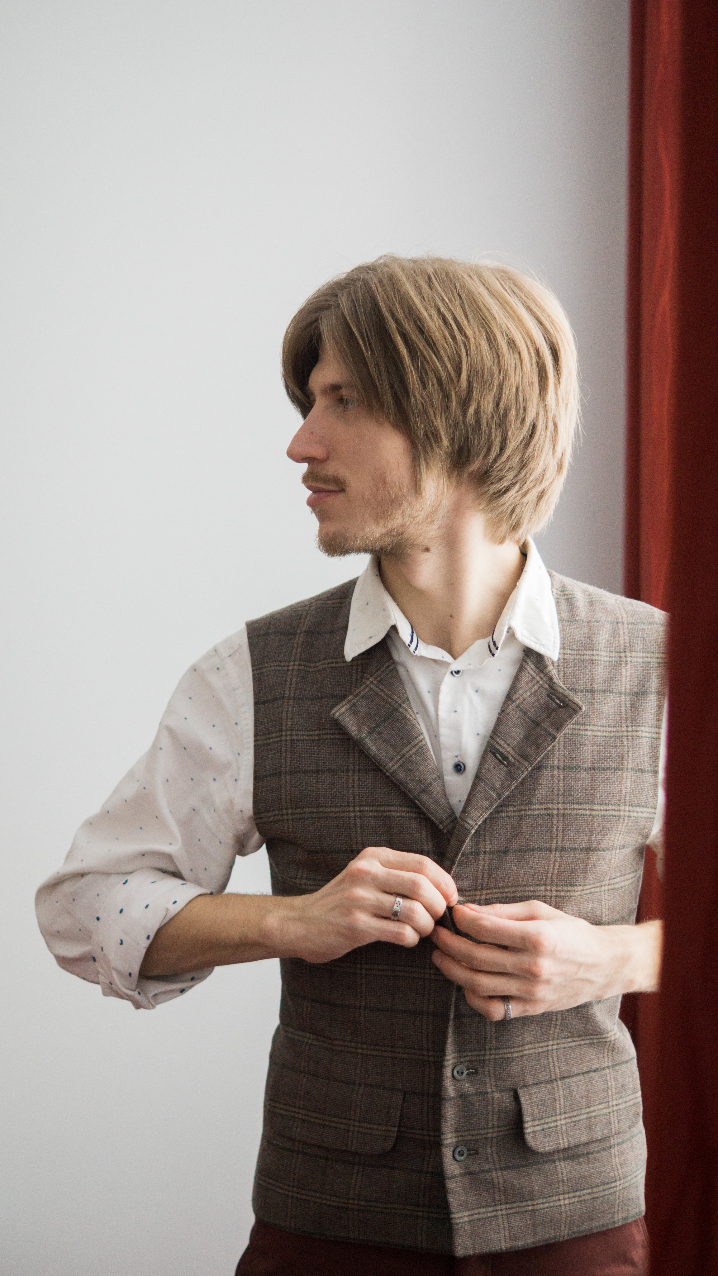 Жених у окна, застегивает жилет и смотрит в окно, естественное освещение