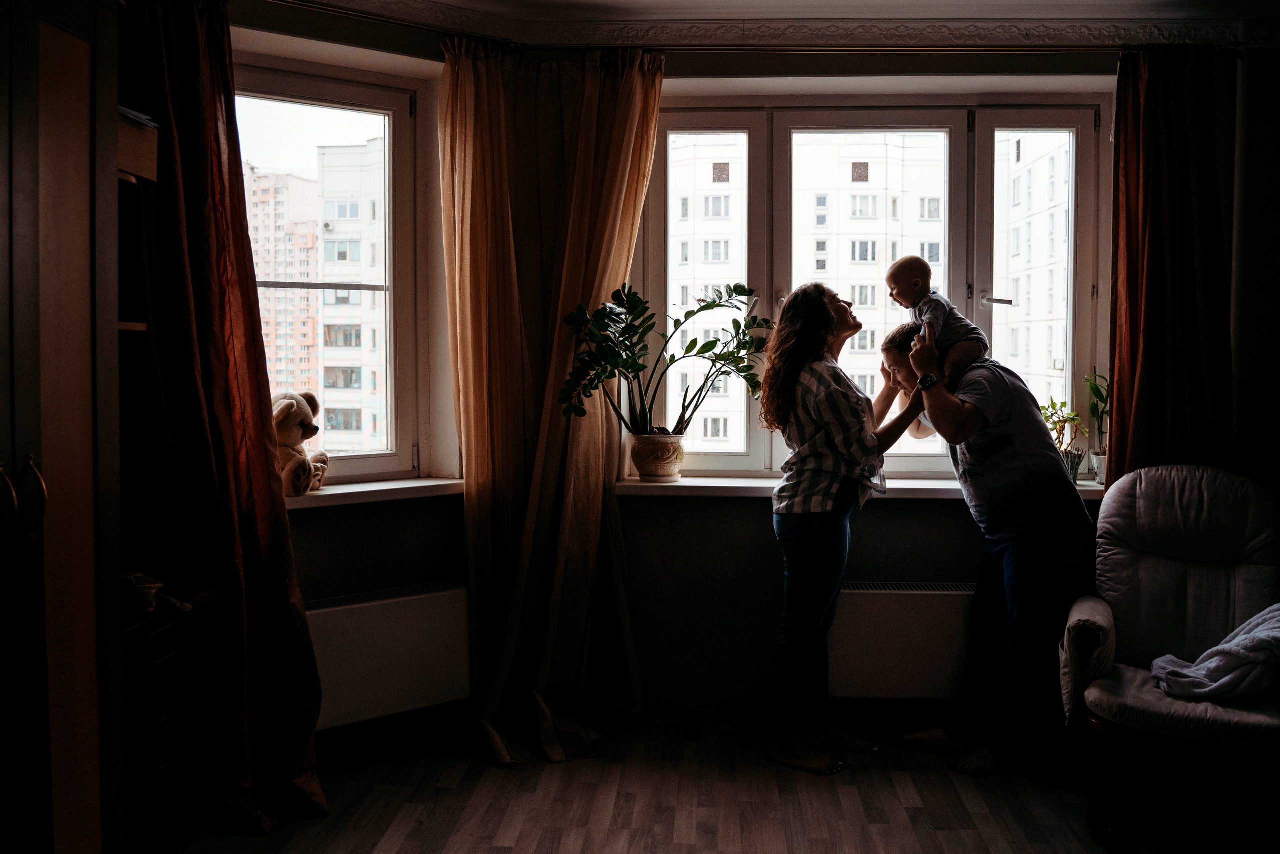 мама и папа играют с ребенком у окна