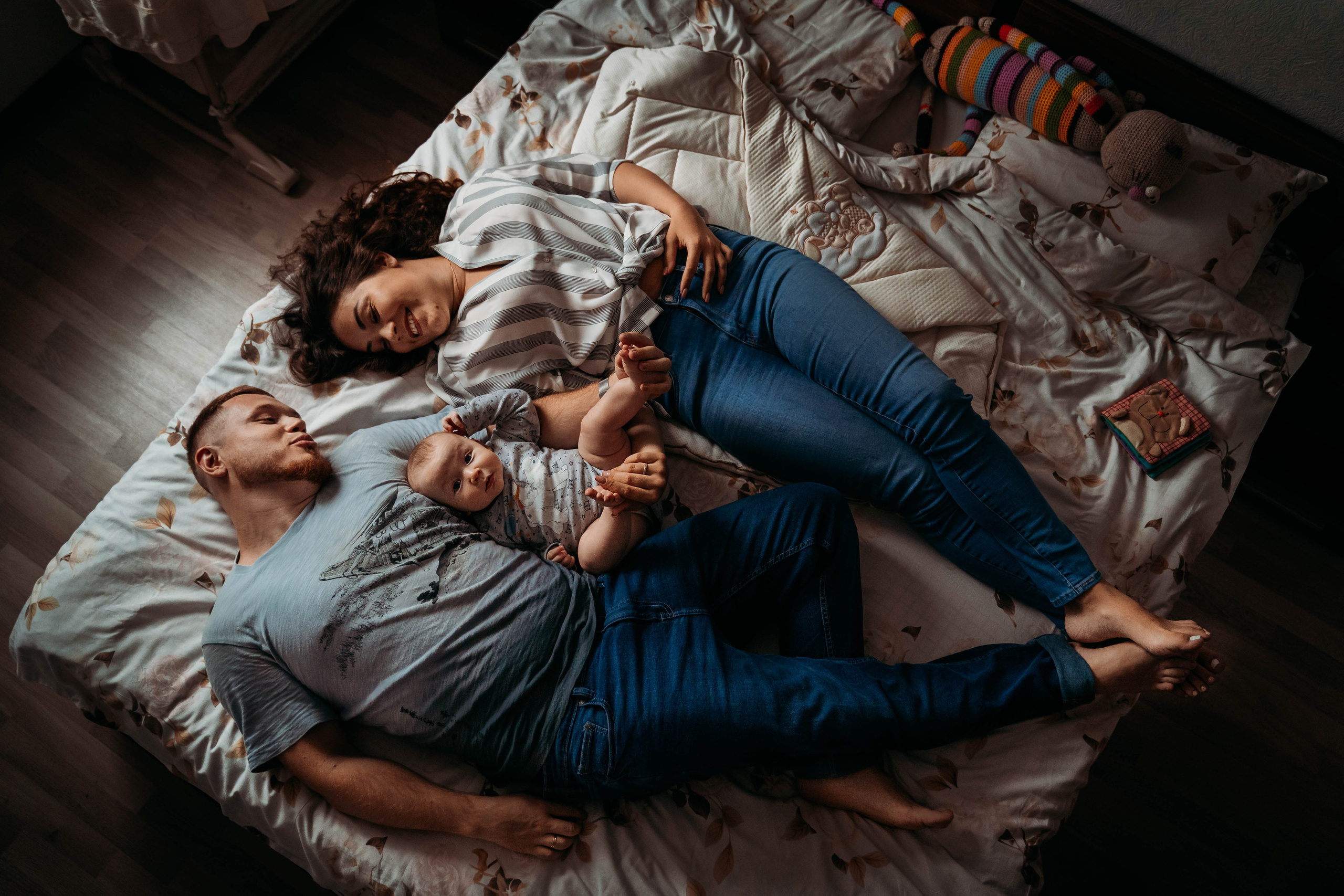 семейный портрет лежа на кровати. Мама, папа и малыш по середине