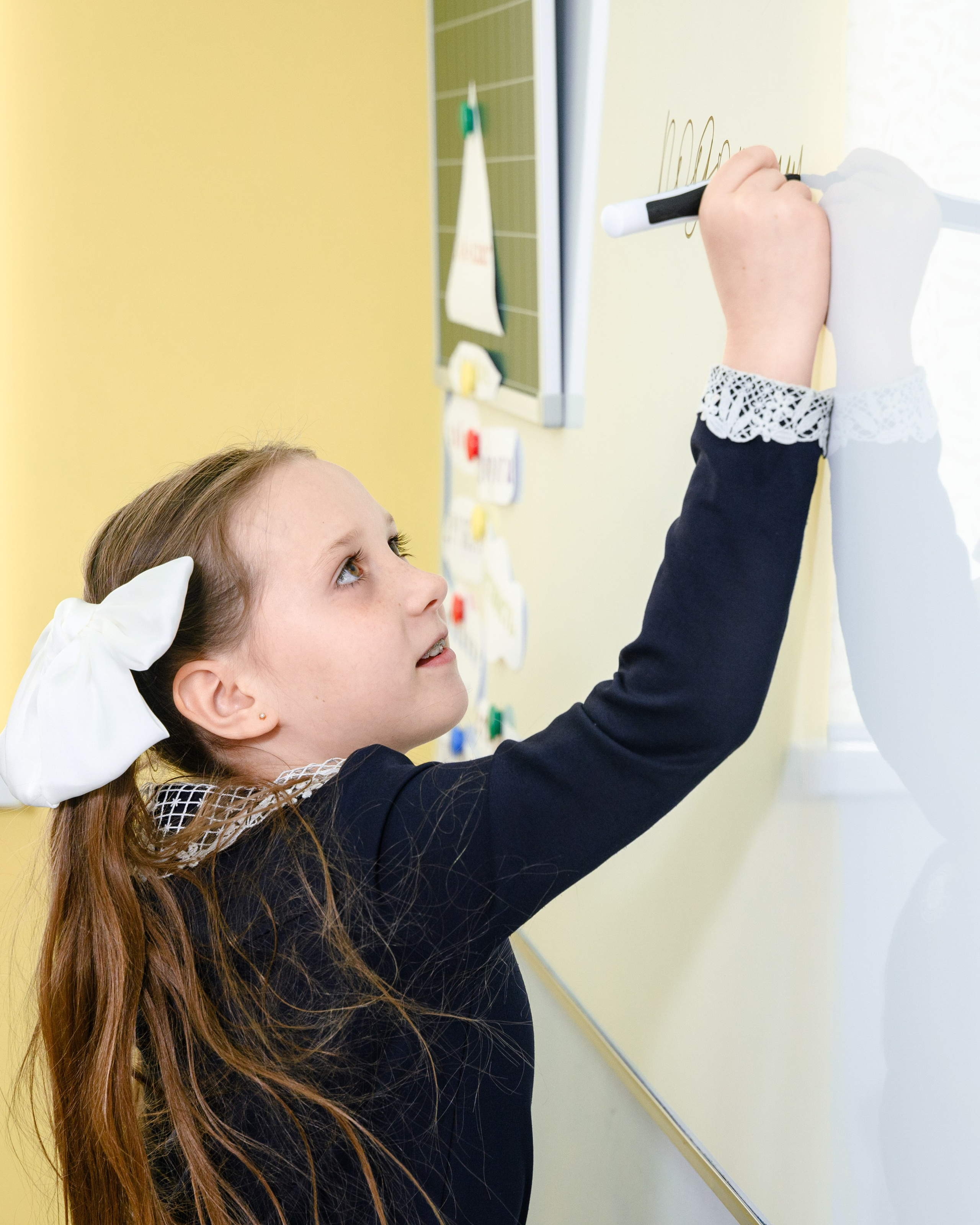 Школьница пишет маркером на доске во время урока