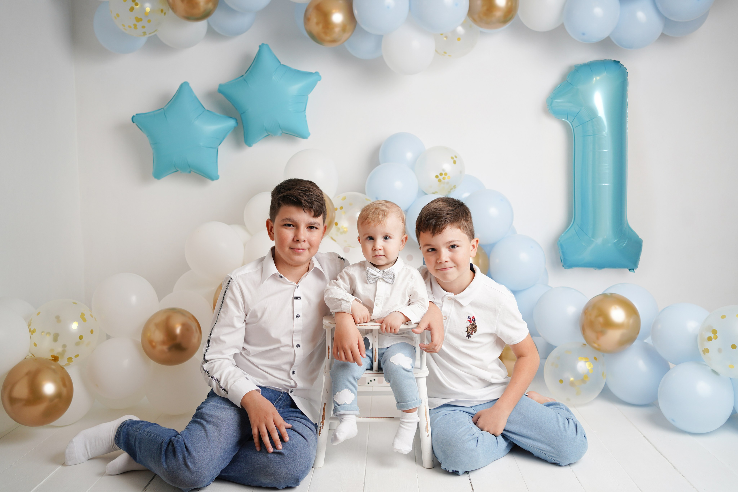 На фото три братика. Фотостудия оформлена голубыми воздушными шарами.