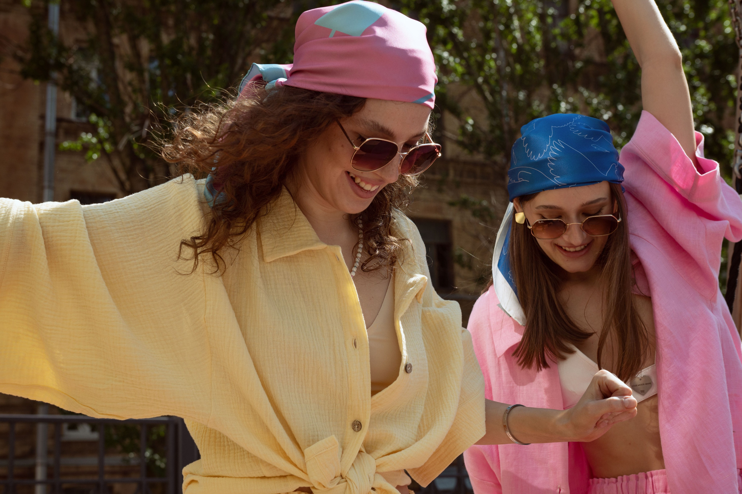 Две красивые девушки в дизайнерской одежде и шелковых дизайнерских платках смеются