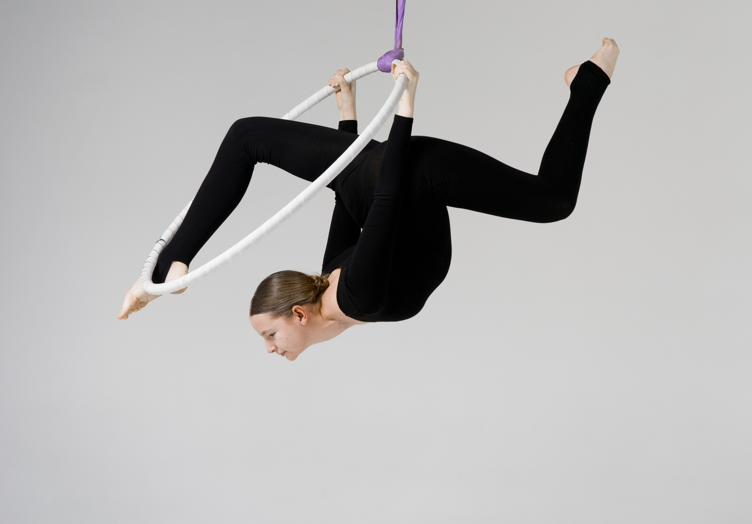 Сложный силовой шпагат на воздушном снаряде, профессиональный кадр гимнастки в перевернутом положении