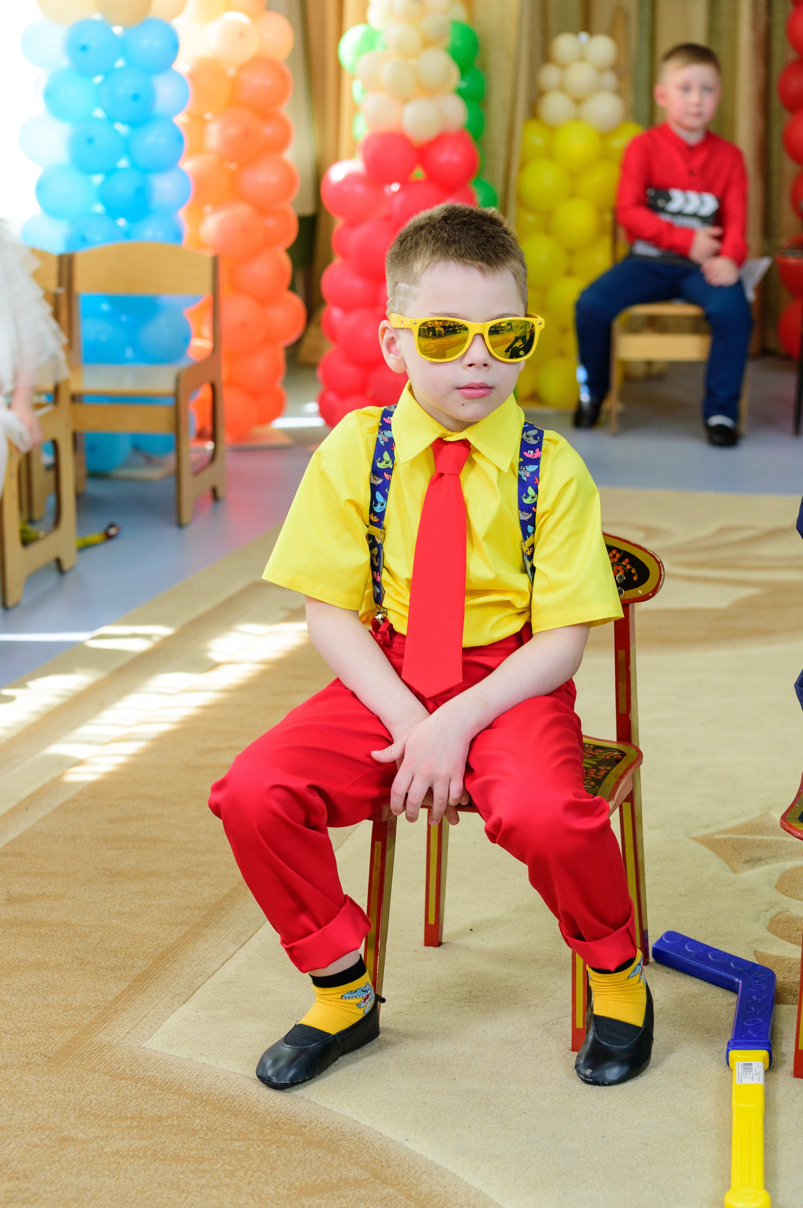 Сценка в детском саду. Мальчик в костюме стиляги сидит на стуле.