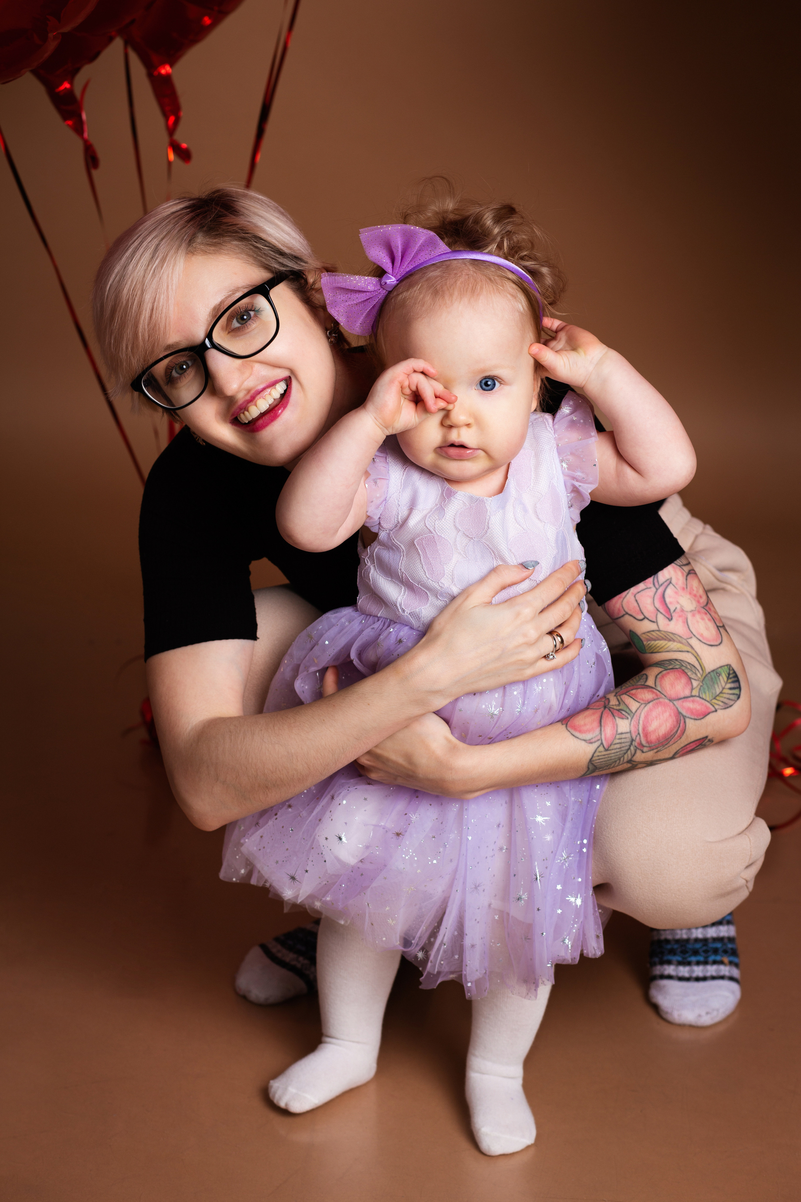девушка  в очках  держит  ребенка  в сиреневом платье