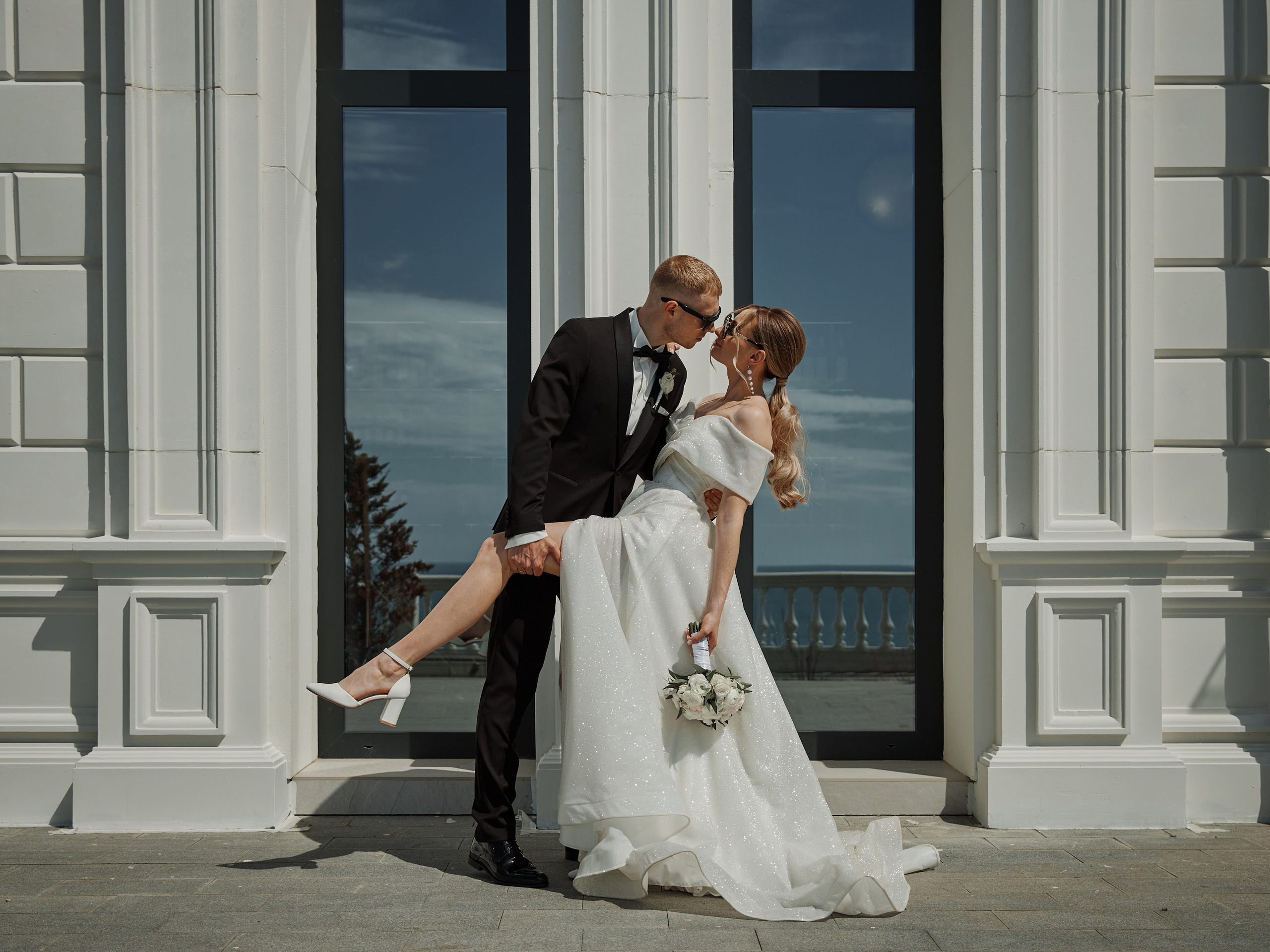 Жених обнимает невесту возле витрины на набережной Анапы