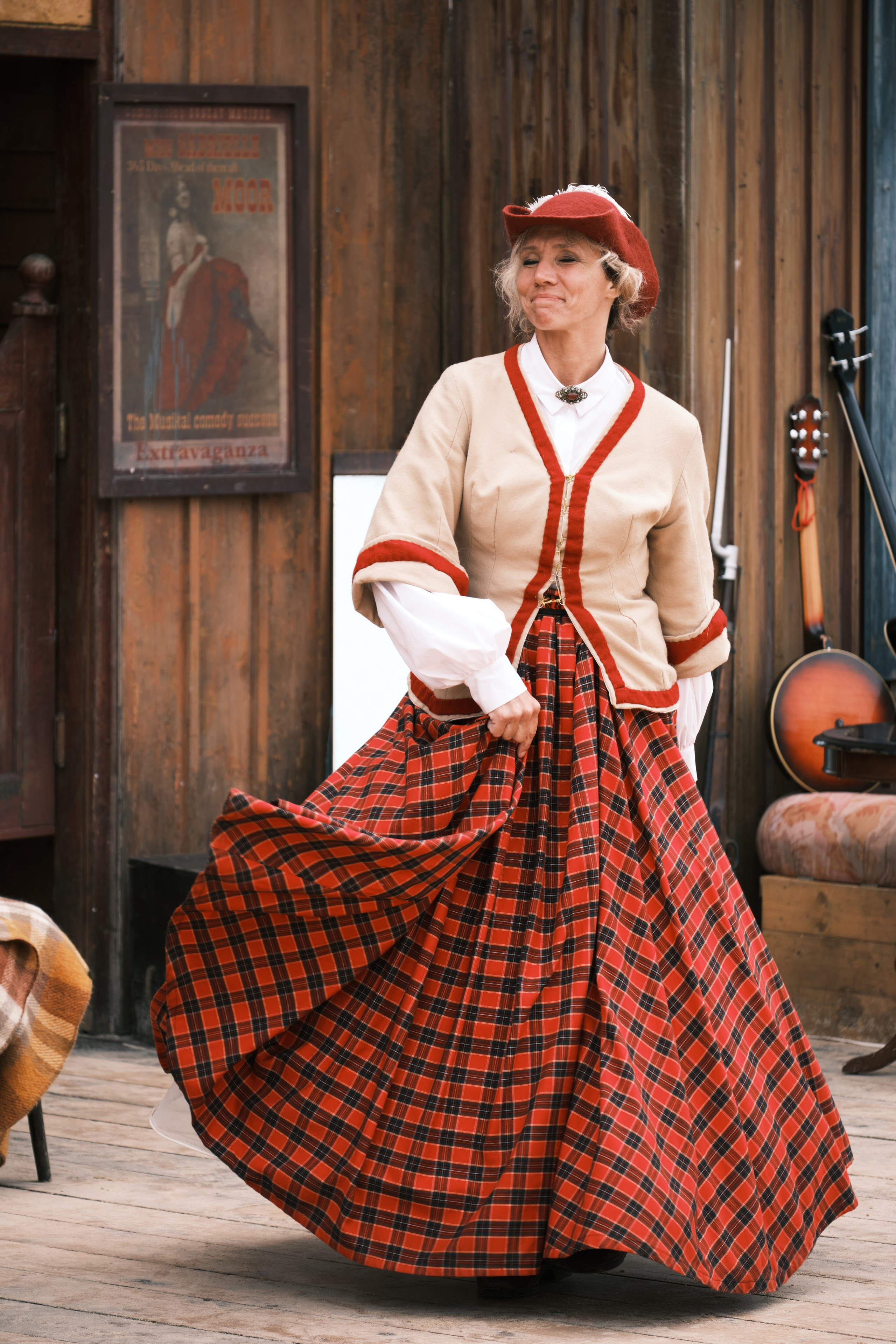 Девушка в красном платье танцует возле салона в ковбойском городке