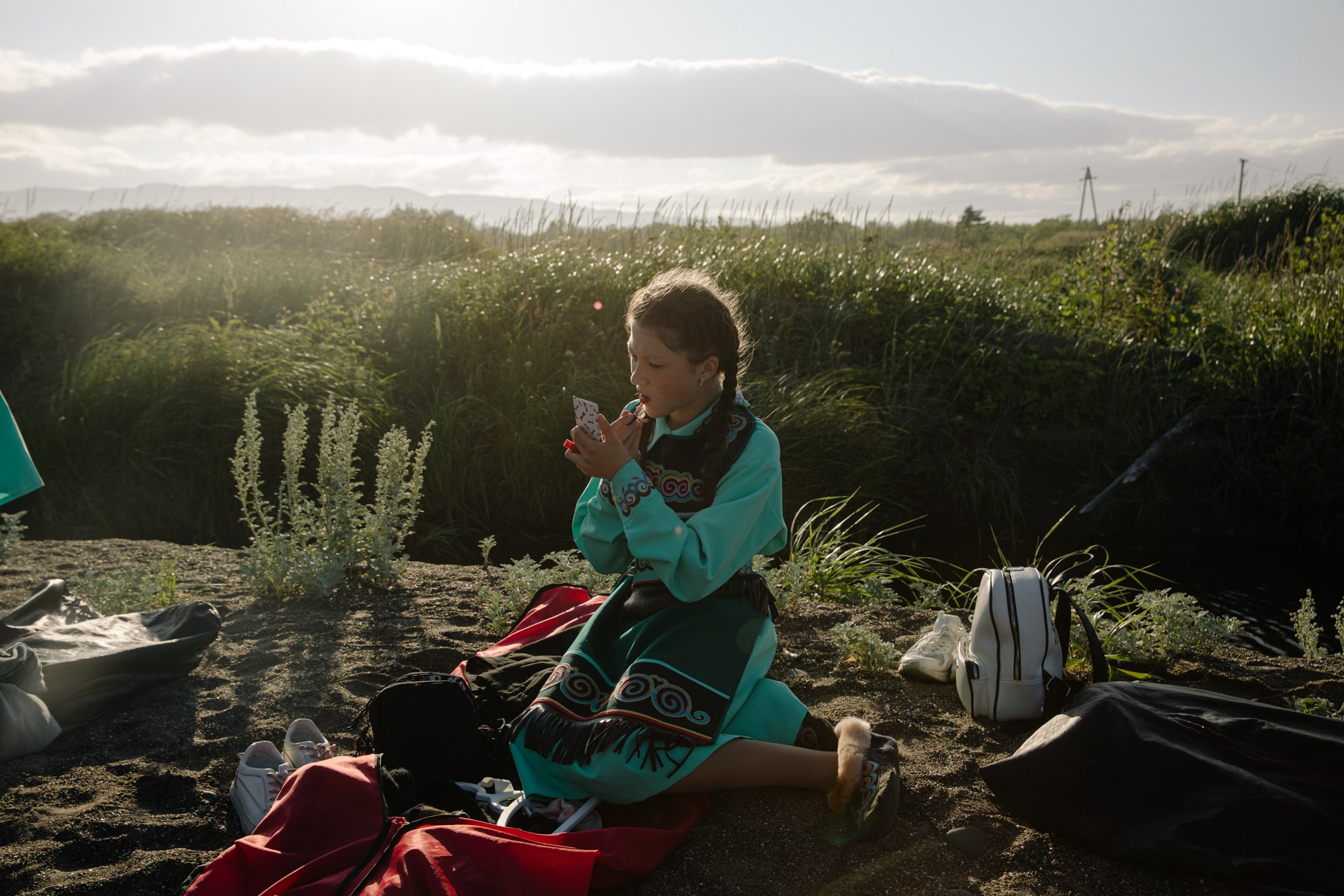 A girl from the folk ensemble "Mengume Ilga" (Silver Patterns) is applying lipstick to her lips before a performance.