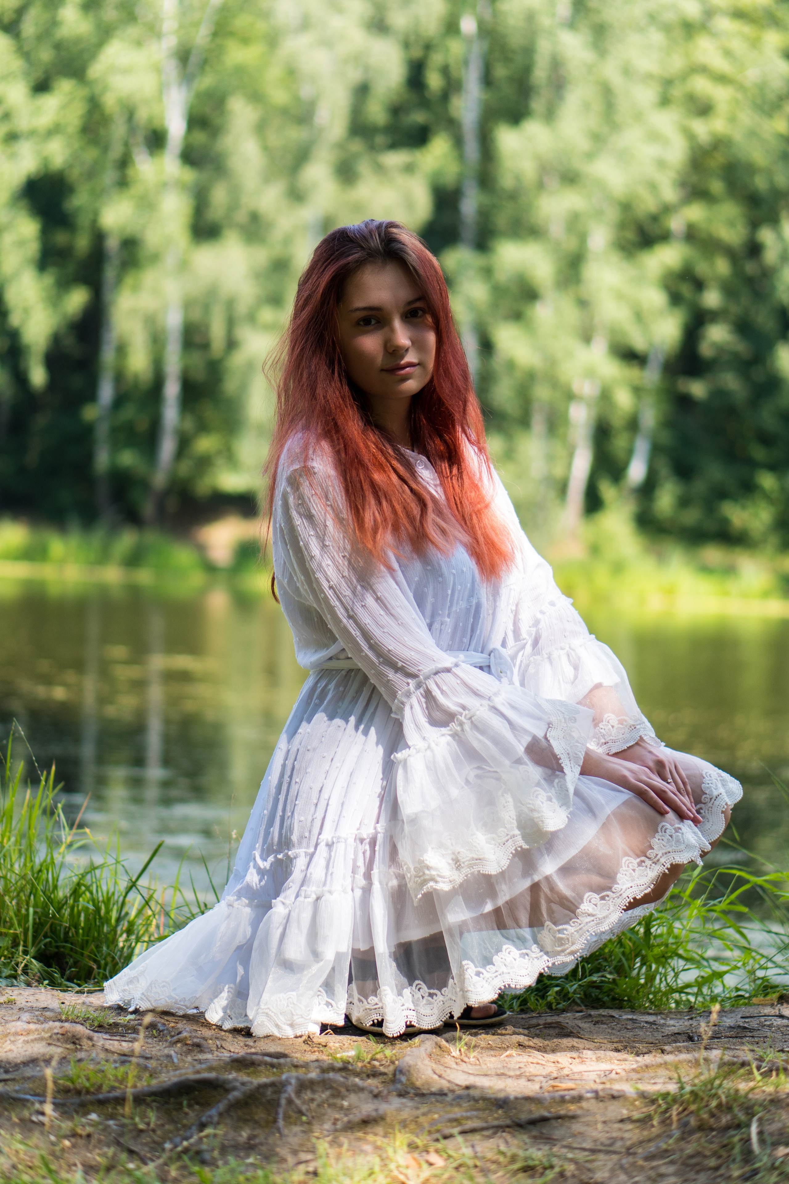 модель в белом кружевном платье сидит около пруда в усадьбе Архангельское