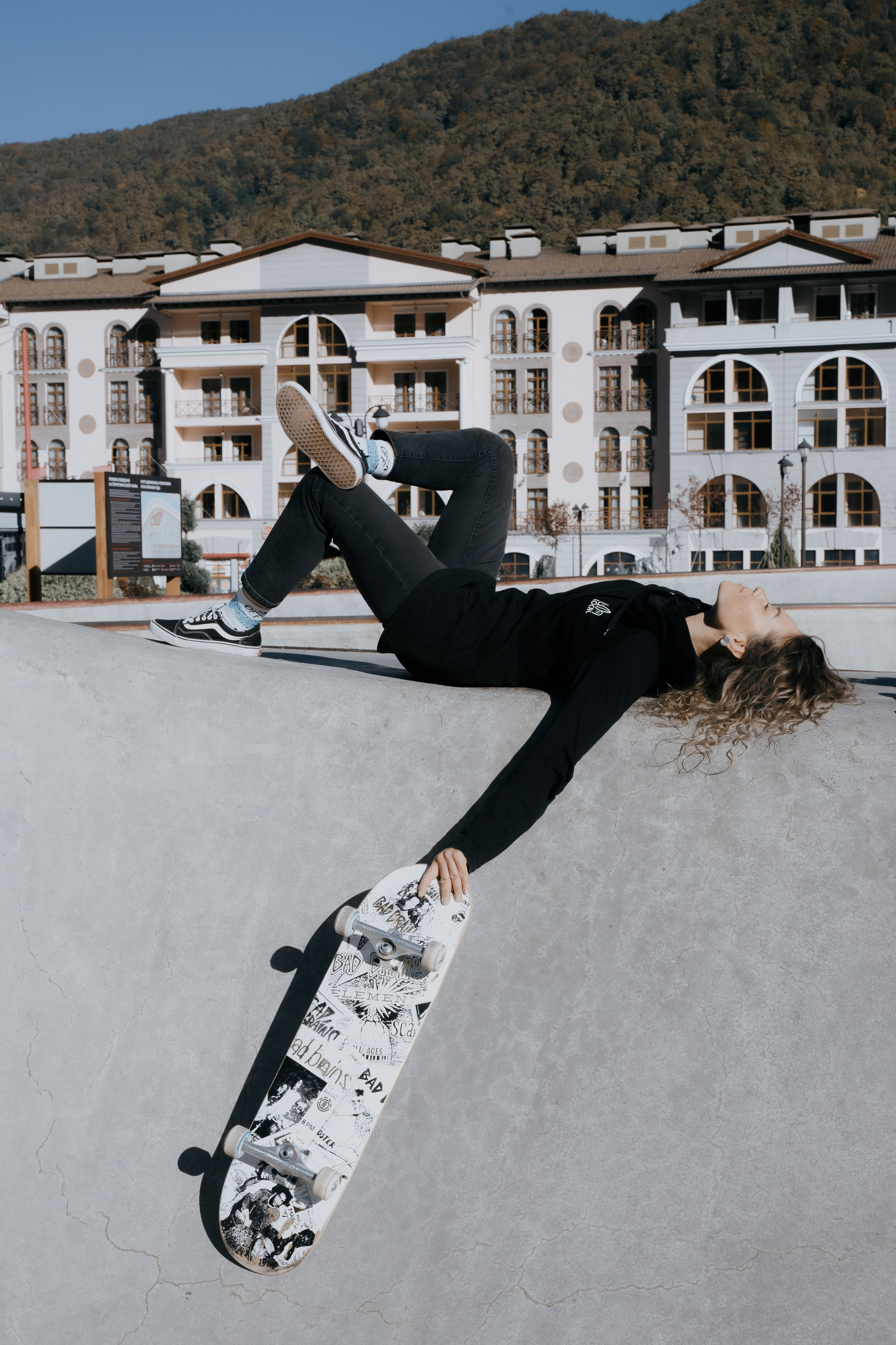 Портретный снимок девушки лежащий на полу со скейтом