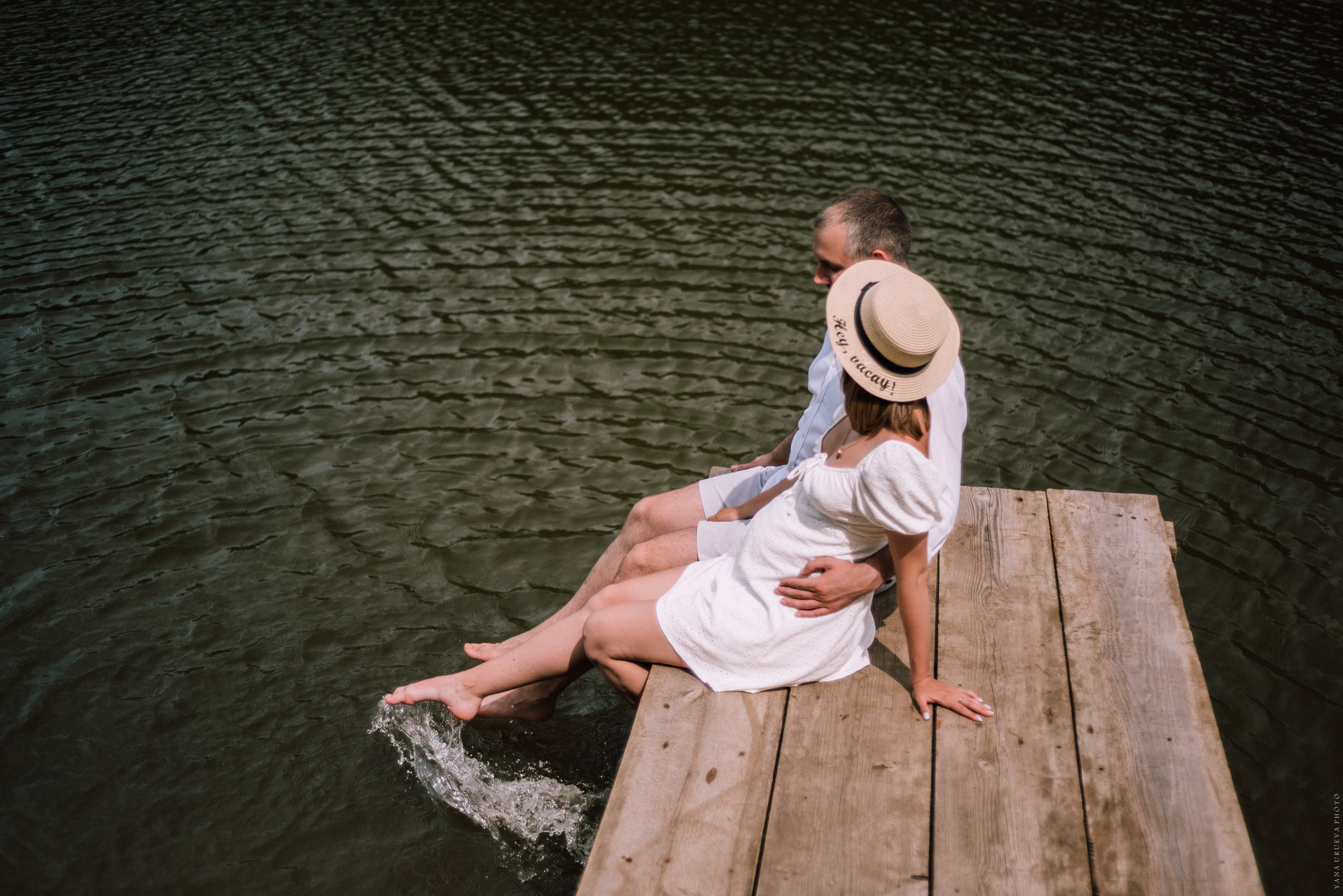 девушка опустила ноги в реку и сидит на пирсе