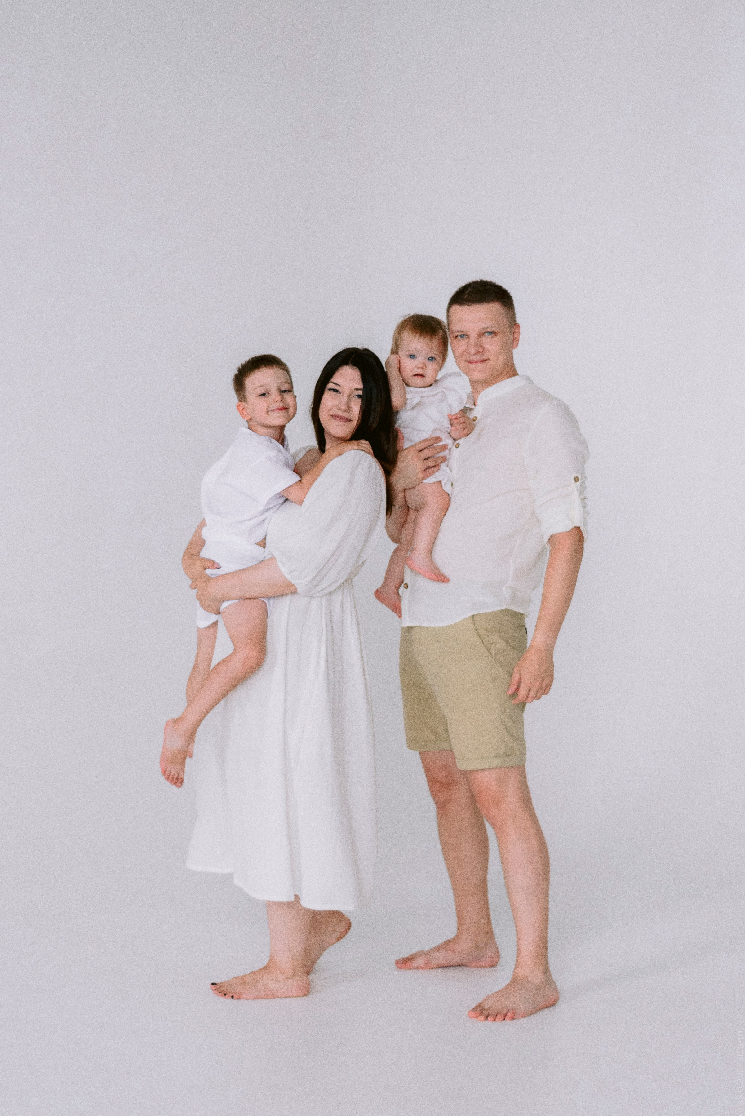 Семейная фотосессия с двумя деться в светлой одежде в студии