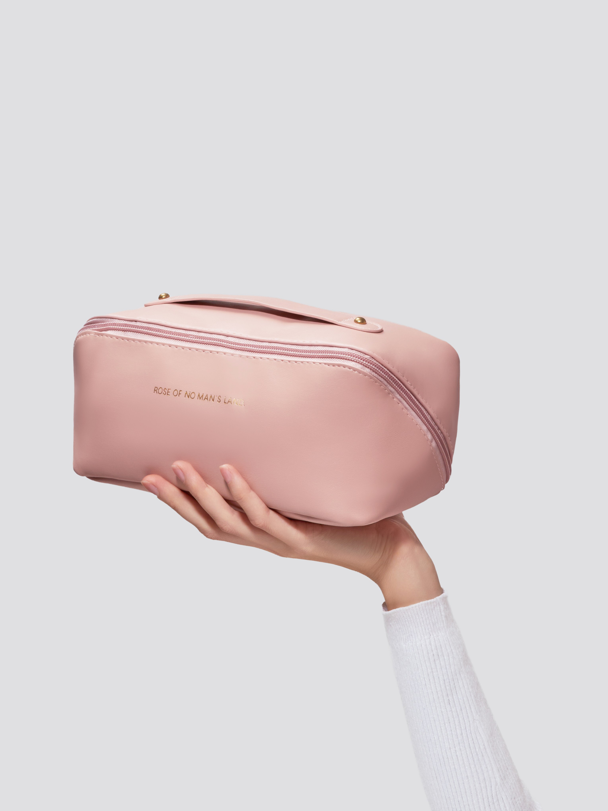 Предметная рекламная фотосъёмка розовой косметички в руках модели на белом фоне