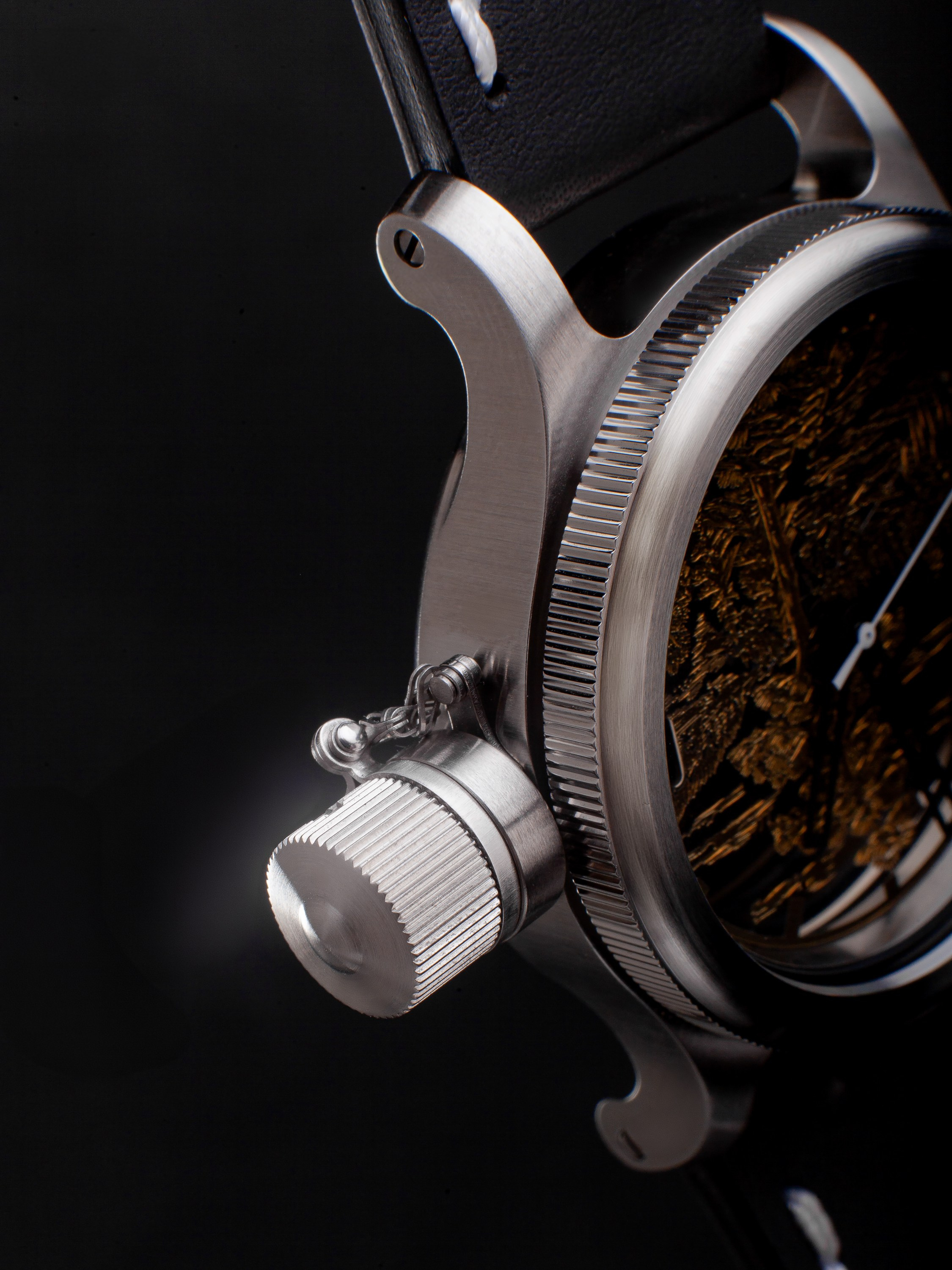 макро съемка заводной головки наручных часов из матовой стали, предметная фотография корпуса с акцентом на текстуру металла и детали механики