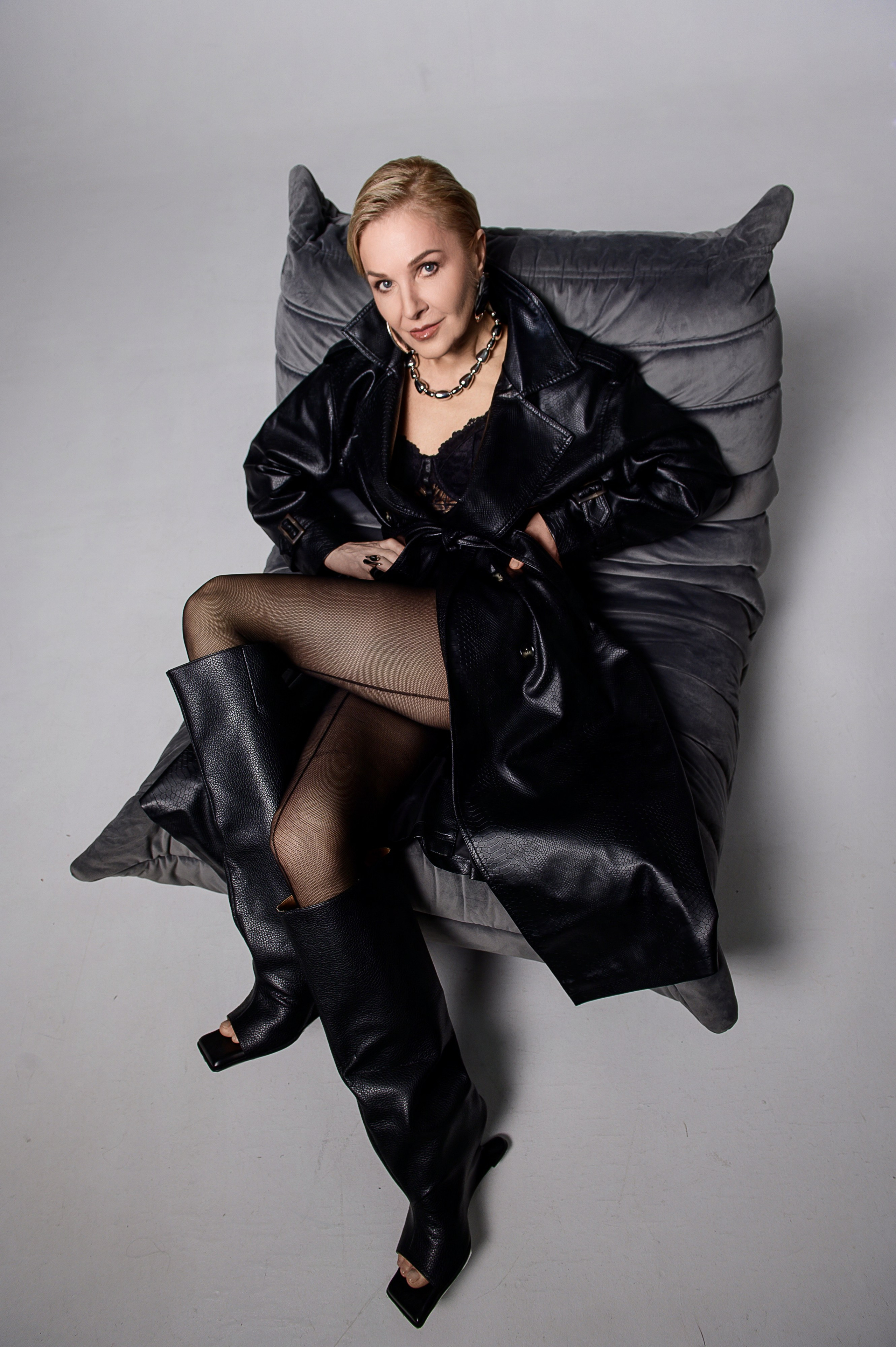 Фэшн-съёмка в Москве — модель в чёрном образе сидит в кресле в студии на светлом фоне