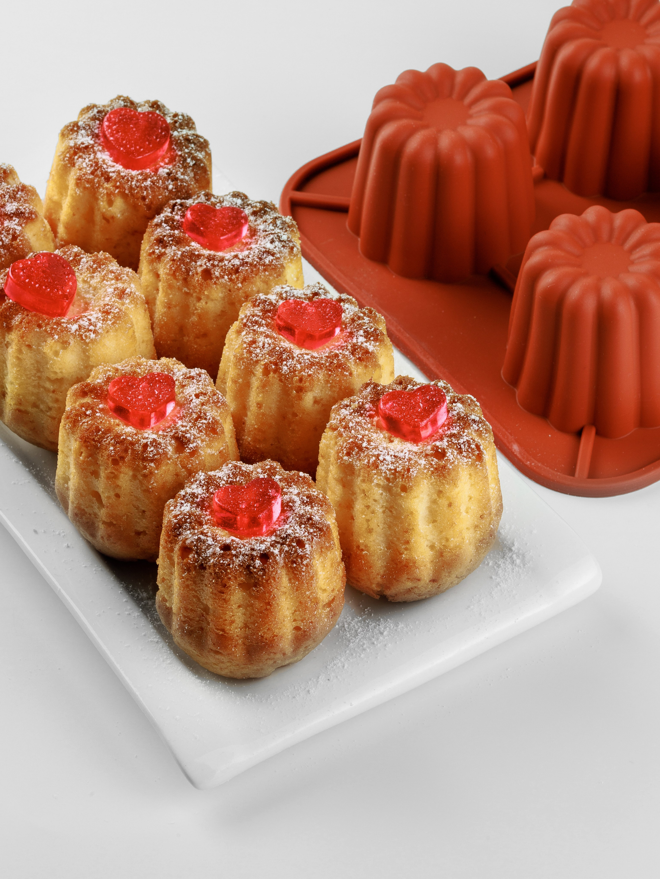 Канеле на белом фоне рядом с силиконовой формой