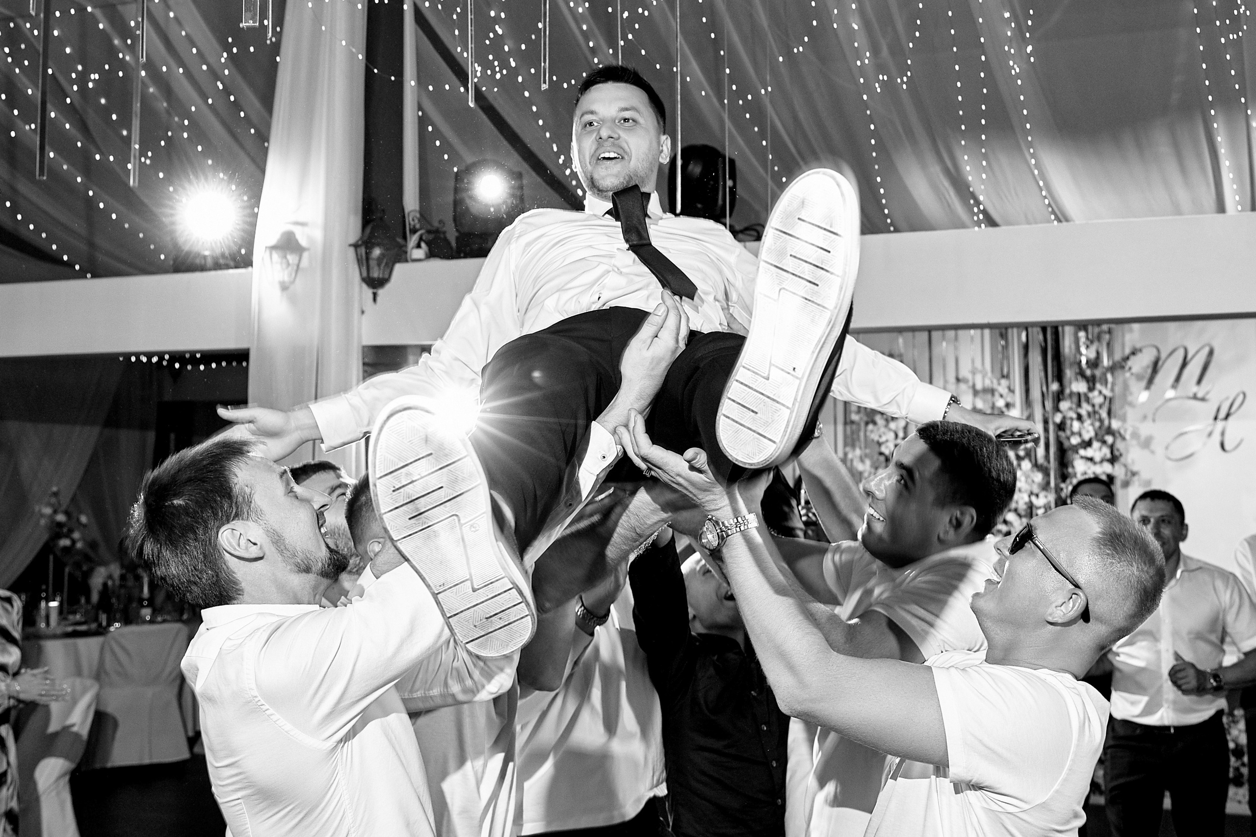 Друзья подбрасывают жениха на руках на свадьбе в Ульяновске — эмоциональный момент веселья. Фотограф Елена Орешина.