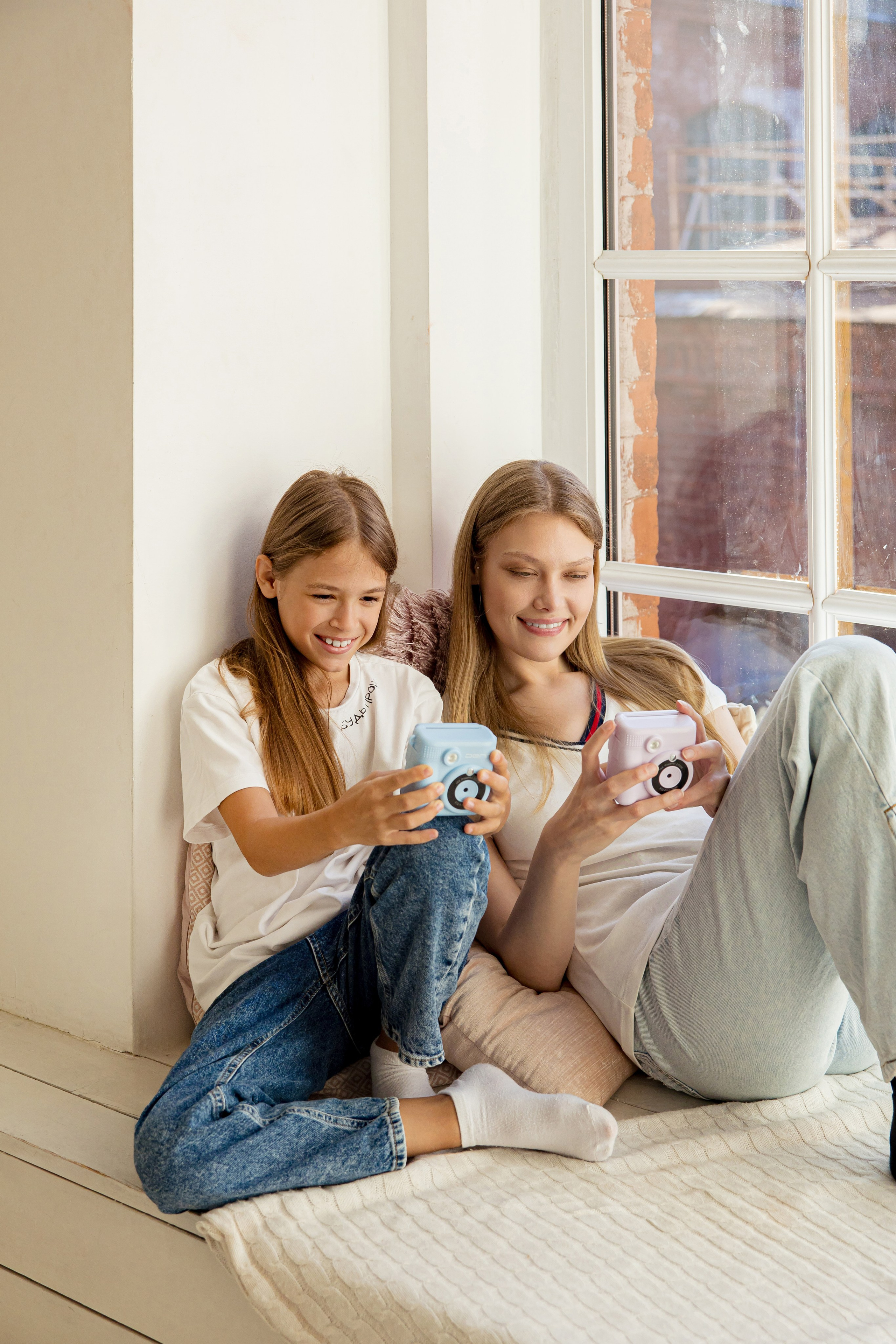 Две девушки с камерами моментальной печати в руках у окна