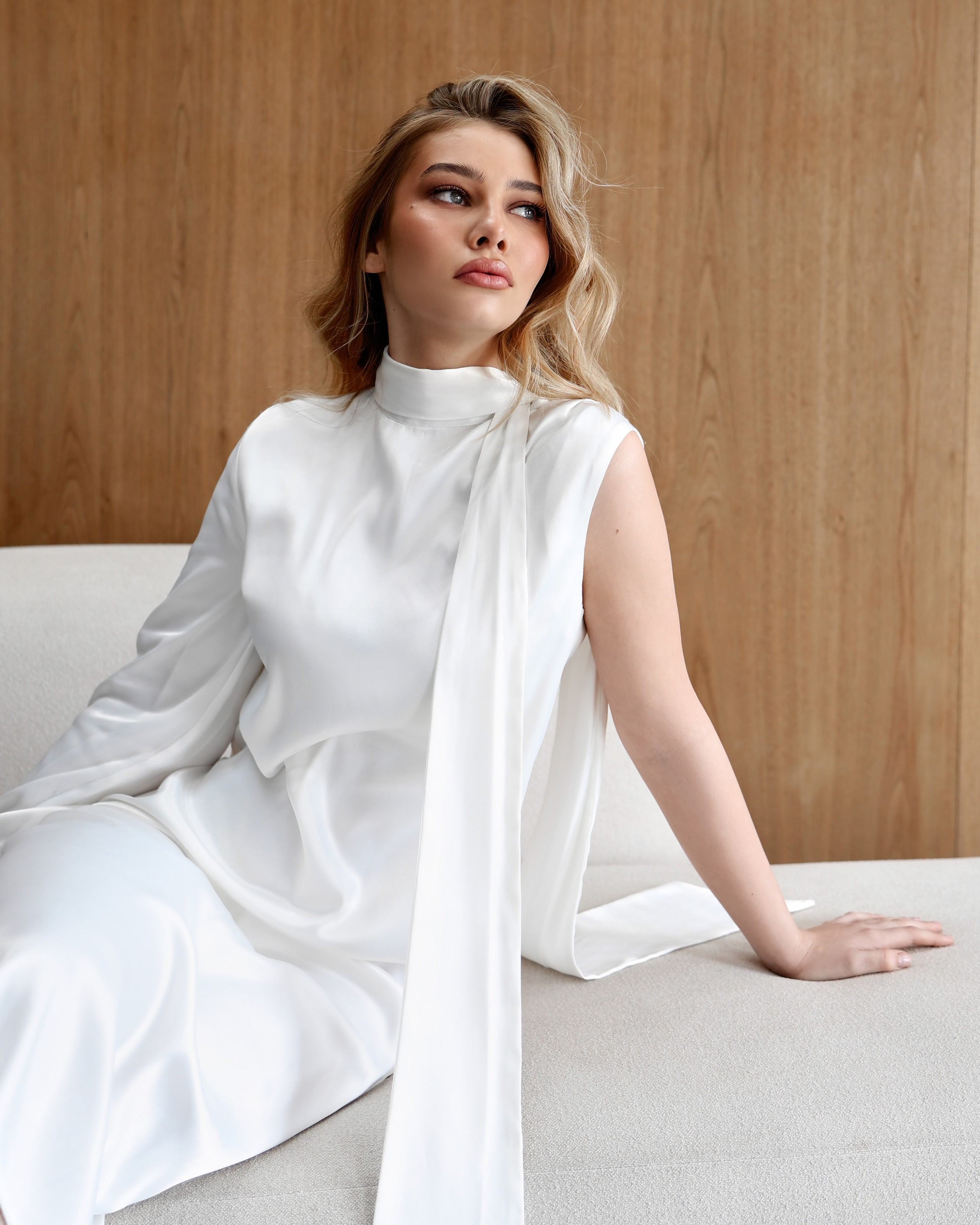 Фотосессия Челябинск в студии для девушки - стильная студийная фотосессия в светлом интерьере с мягким естественным светом, девушка в белом элегантном платье позирует на светлом диване на фоне деревянной стены, минималистичная эстетика, чистый фон, женственная поза, профессиональная фотосессия в студии Челябинск, идеи для фотосессии девушки, вдохновение для съемки, современная портретная съемка, красивая фотосессия для личного бренда, фотосессия для инстаграм, нежные и дорогие визуалы, услуги фотографа Челябинск, студийная фотосъемка для девушек, позирование и стиль для фотосессии, съемка в светлой студии