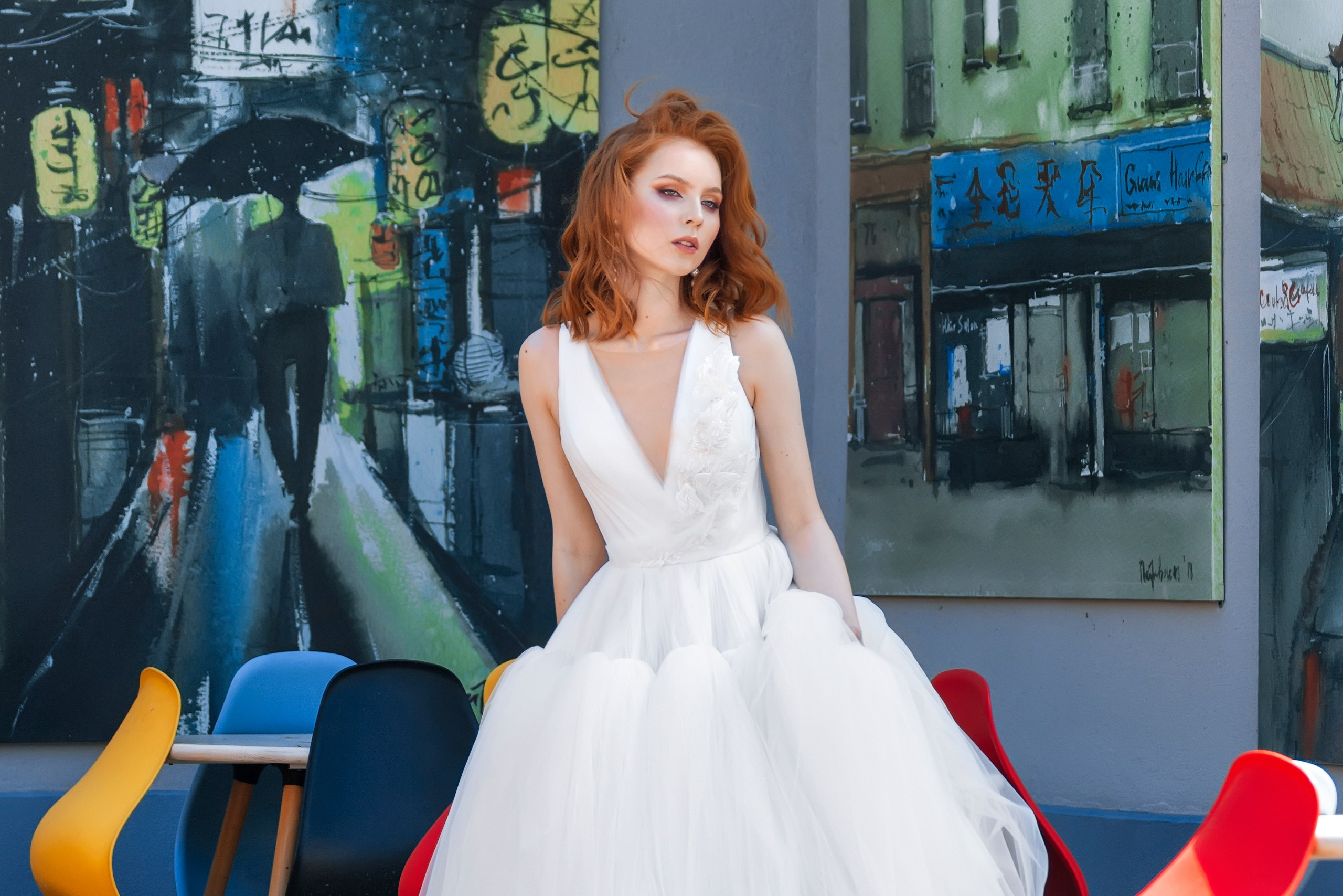 Девушка в свадебном платье на фоне картин в летнем кафе