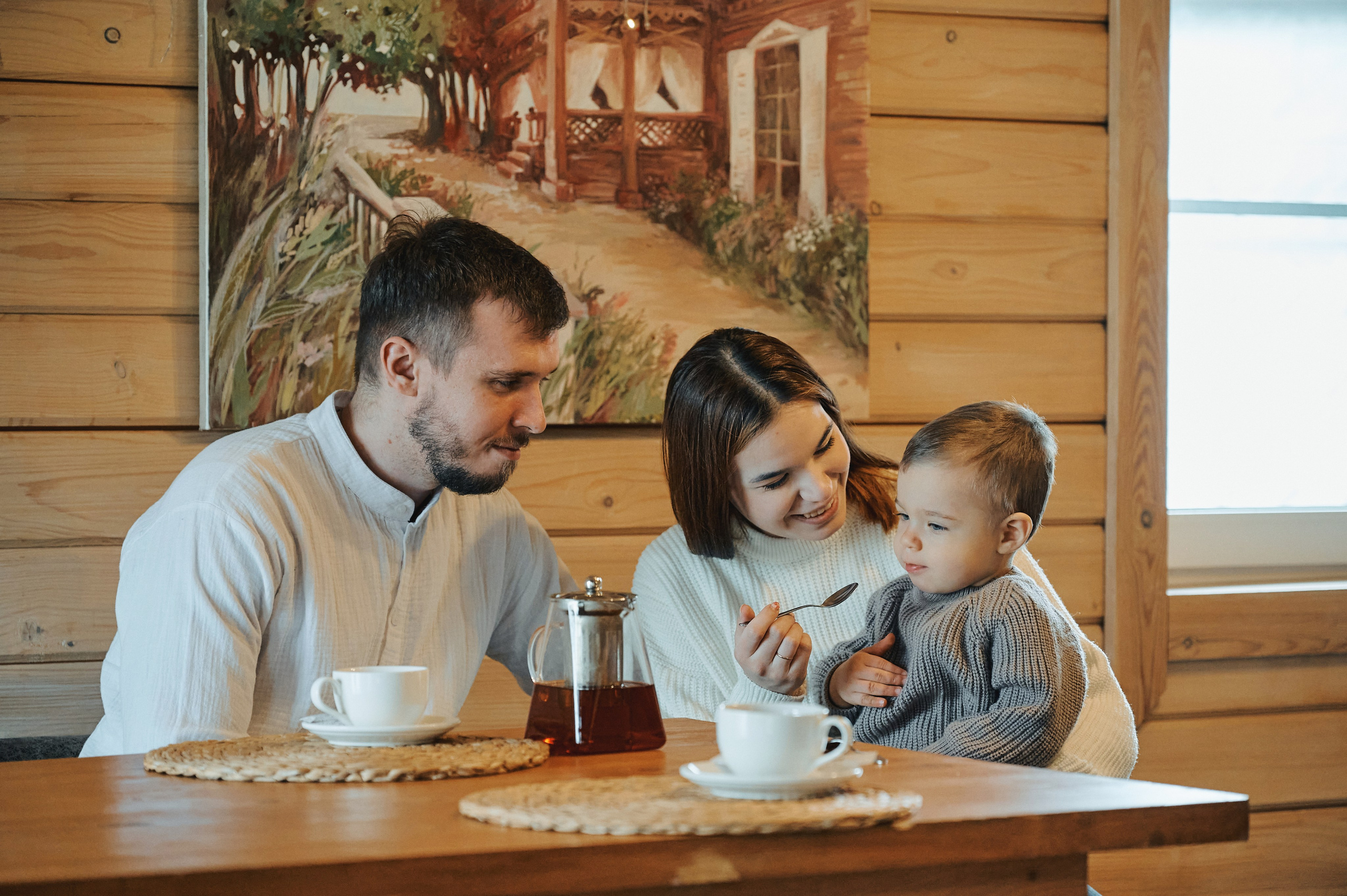Родители с ребёнком за завтраком в уютном деревянном доме.