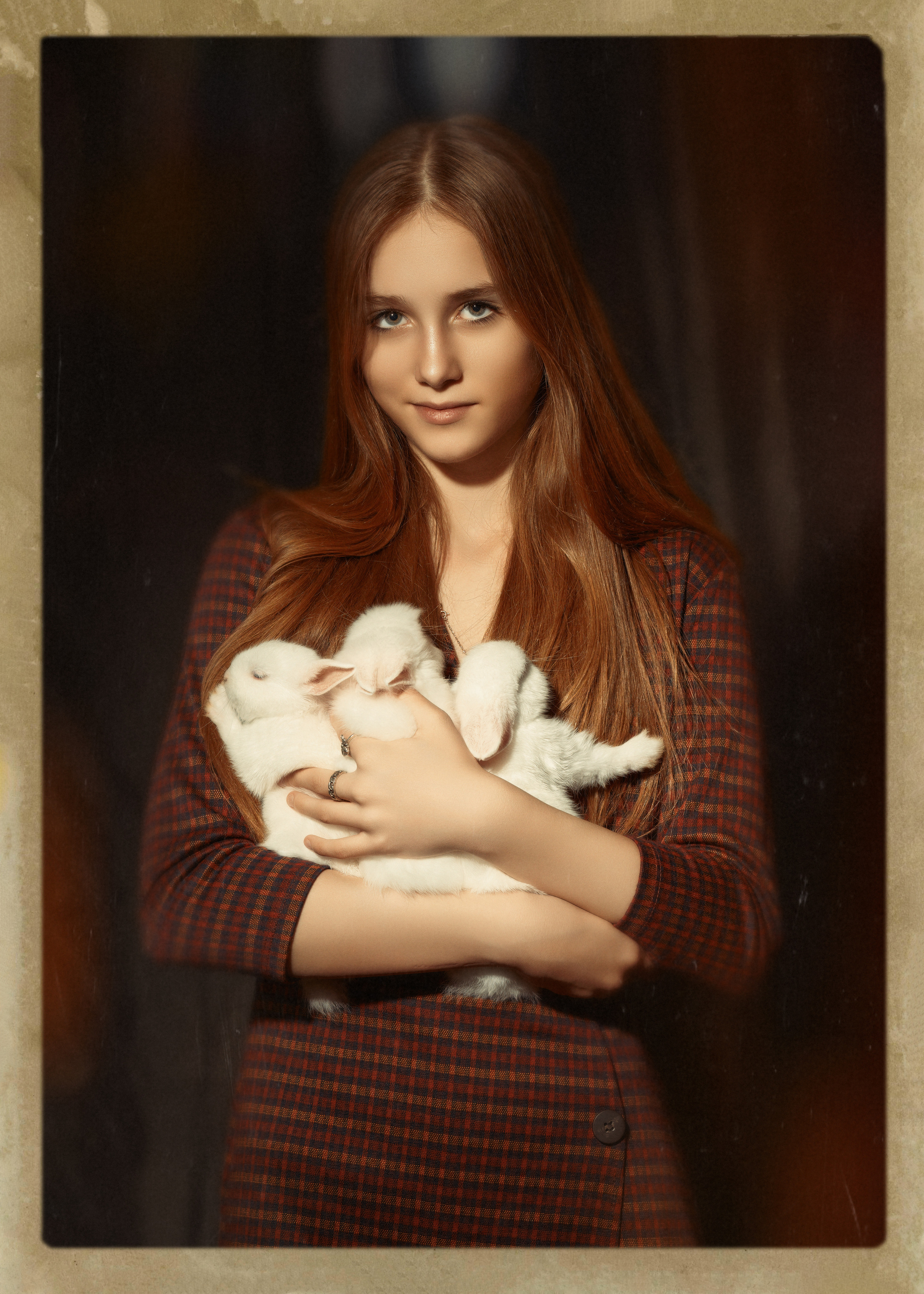 Девушка примерно 16 лет в коричневом платье держит троих кроликов в руках