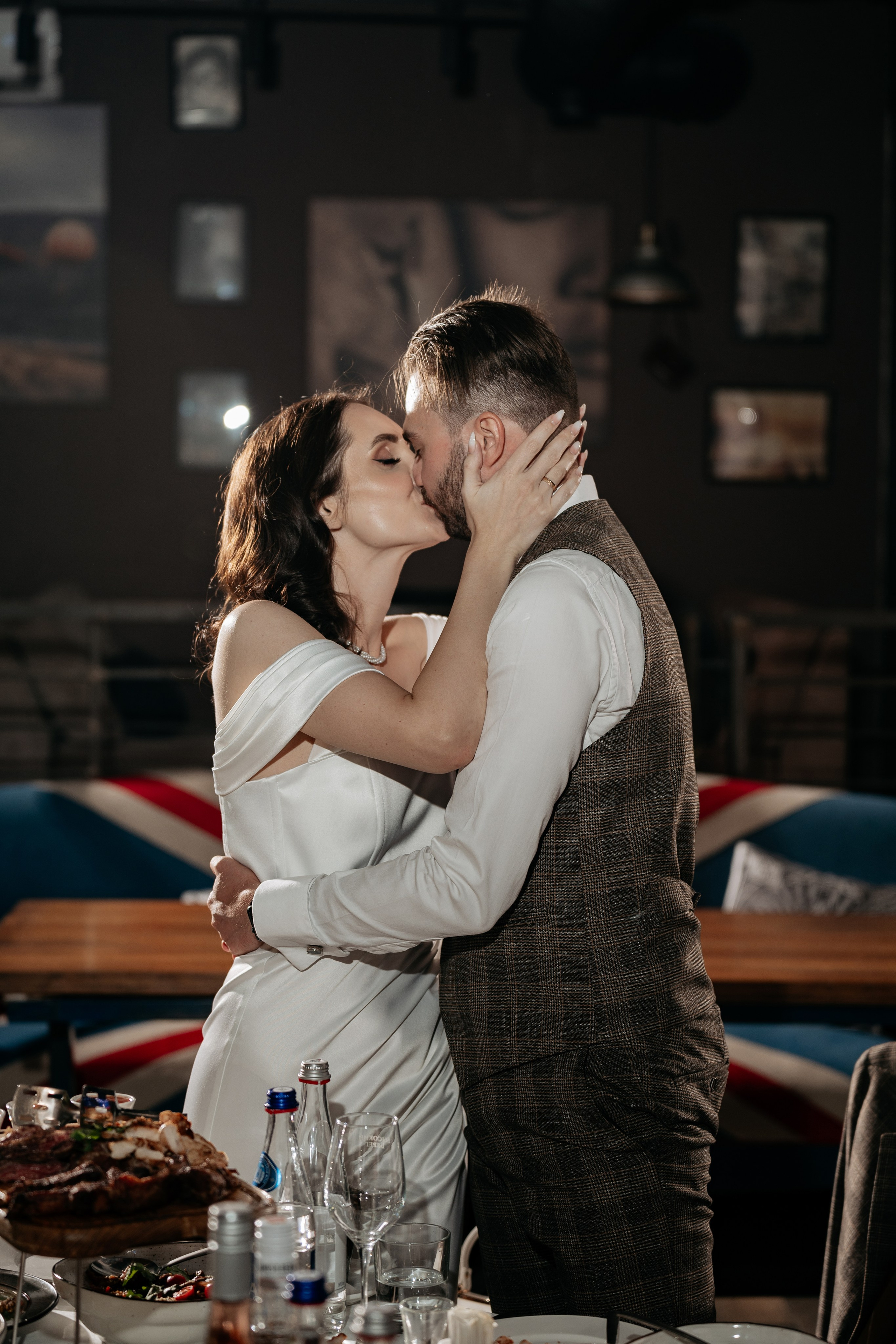 Свадебная фотография на банкете — поцелуй молодожёнов.