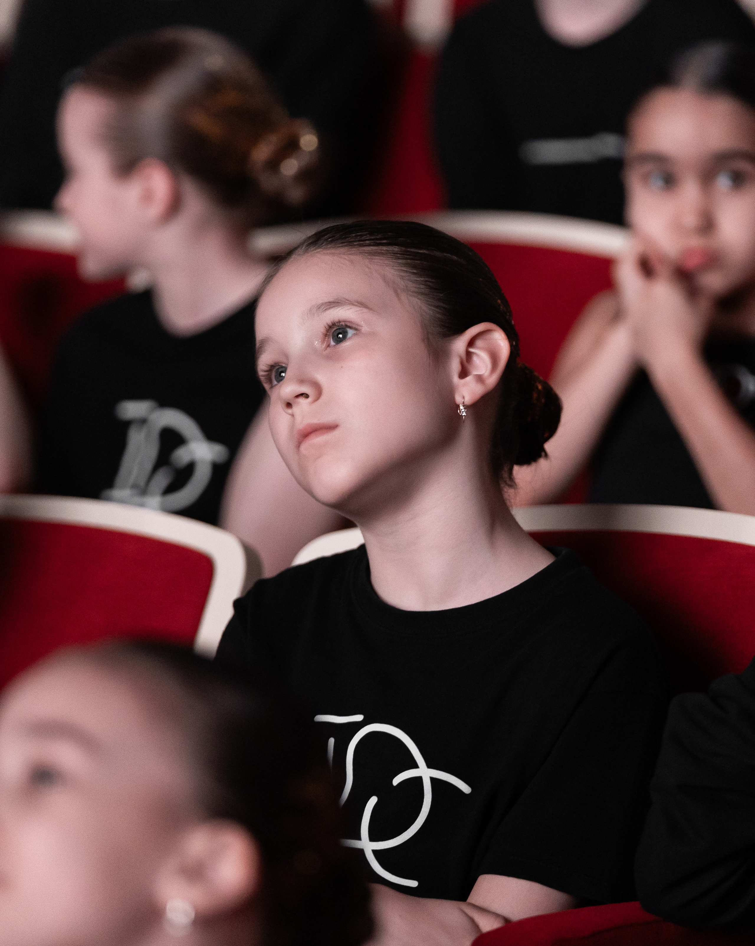 IDC Russia Kids выпускной, девочка в черной футболке с логотипом академии наблюдает за выступлением на сцене Бориса Эйфмана, фото Евгений Мальцев, Санкт-Петербург.