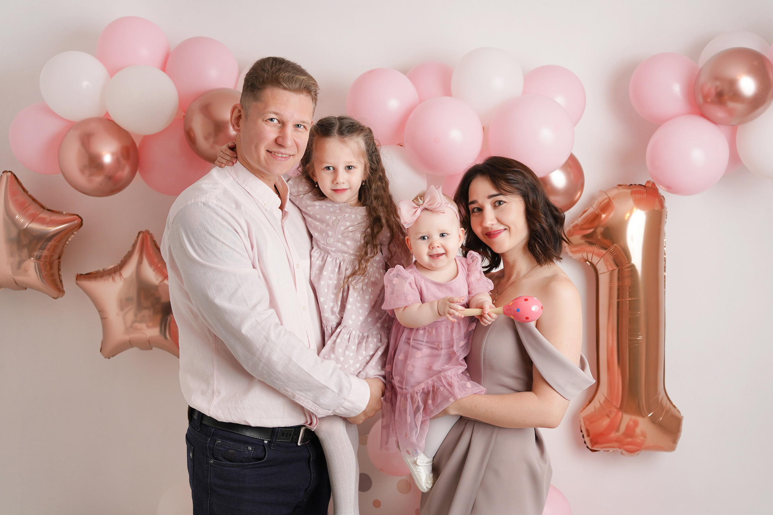 На фото запечатлена семья с двумя детками на фотосессии Первый год. Вокруг много красивых воздушных шаров и атрибуты годовасия.