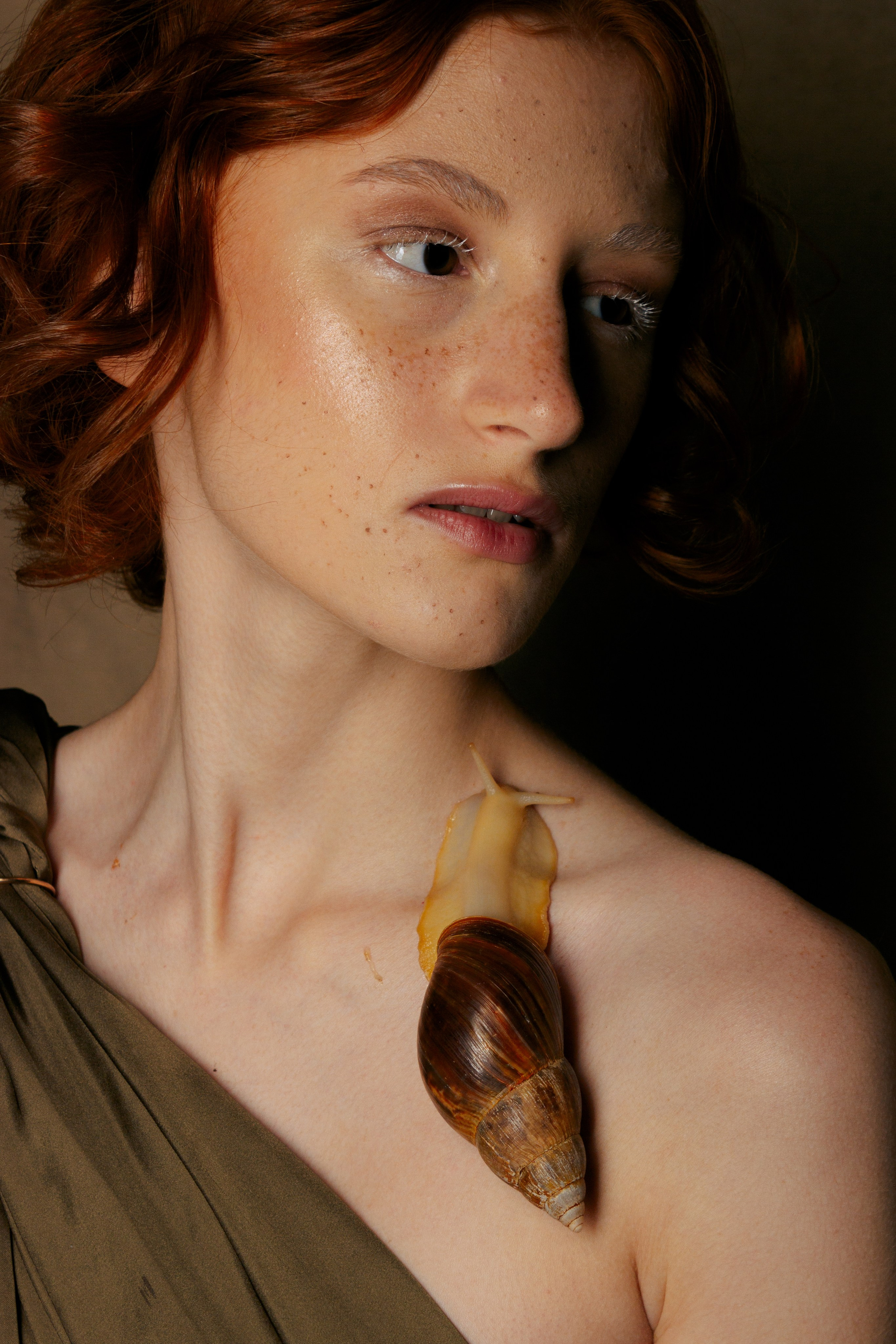 крупный портрет рыжей девушки, на ее ключице расположилась улитка Ахатина