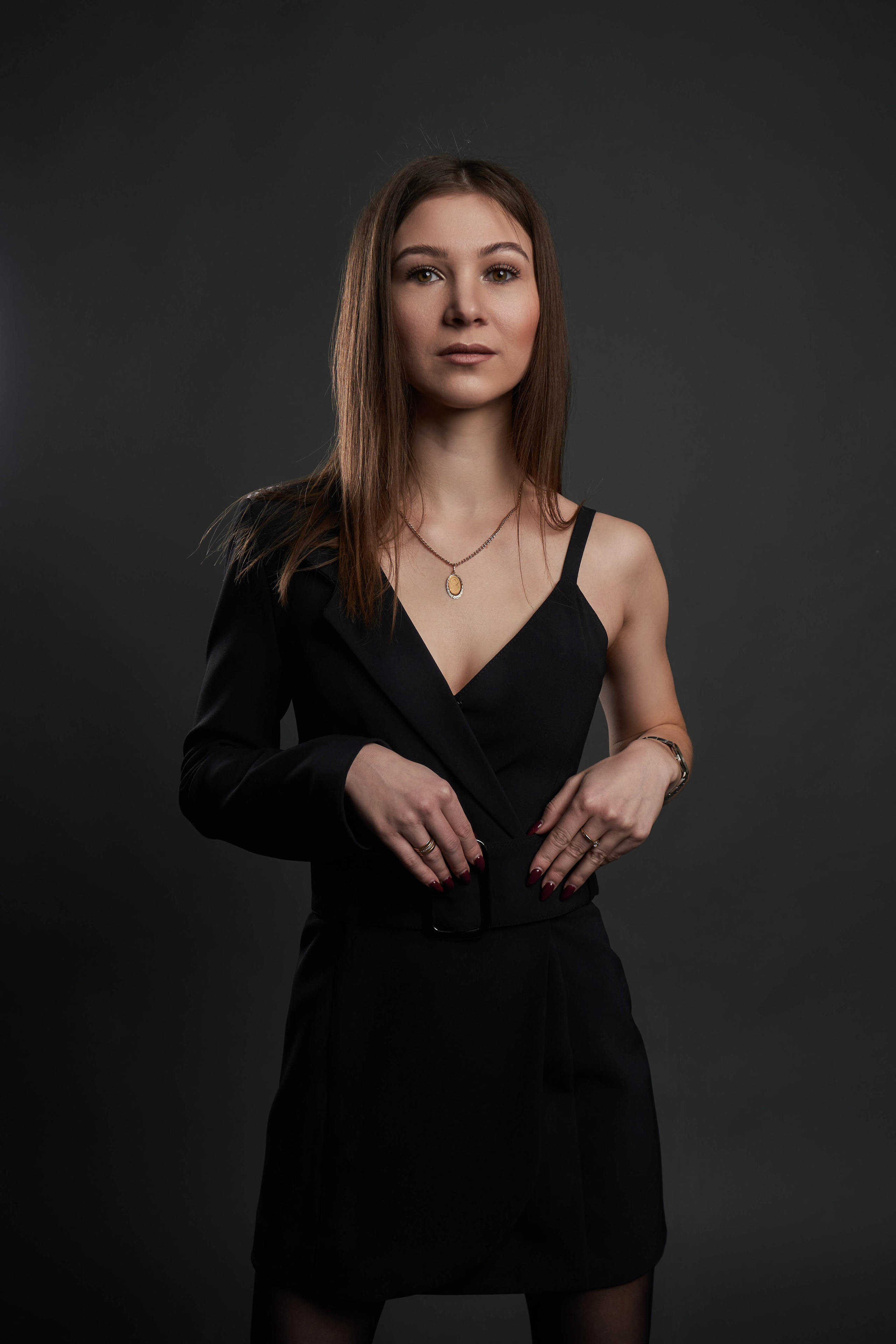 Миниатюрная девушка в черном ассиметричном платье на темном фоне