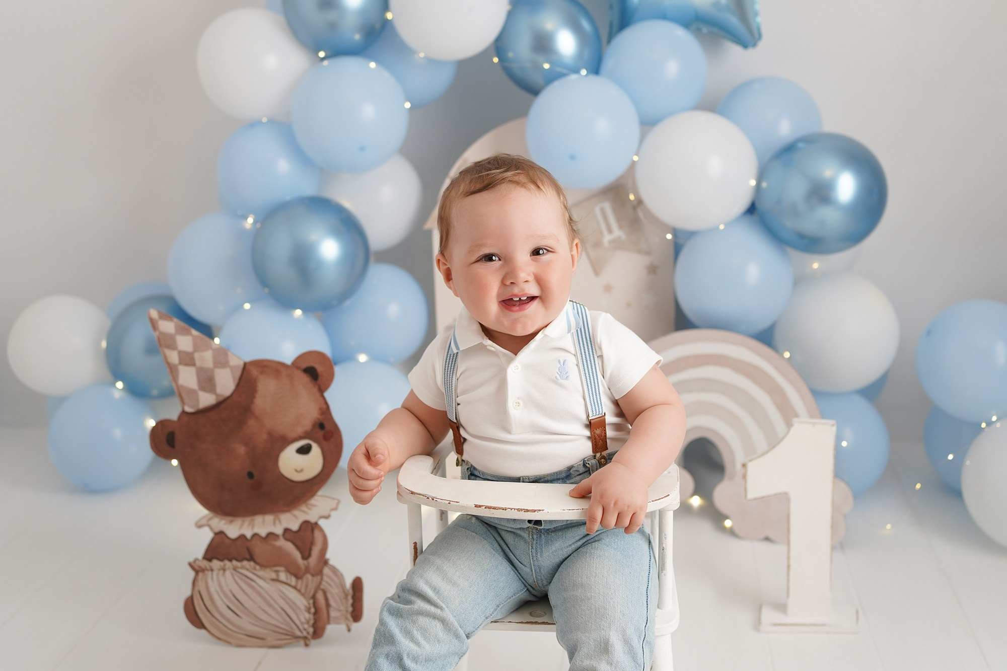 Портрет  малыша на день рождения. Он сидит на стульчике  в окружении голубых шариков и огоньков.