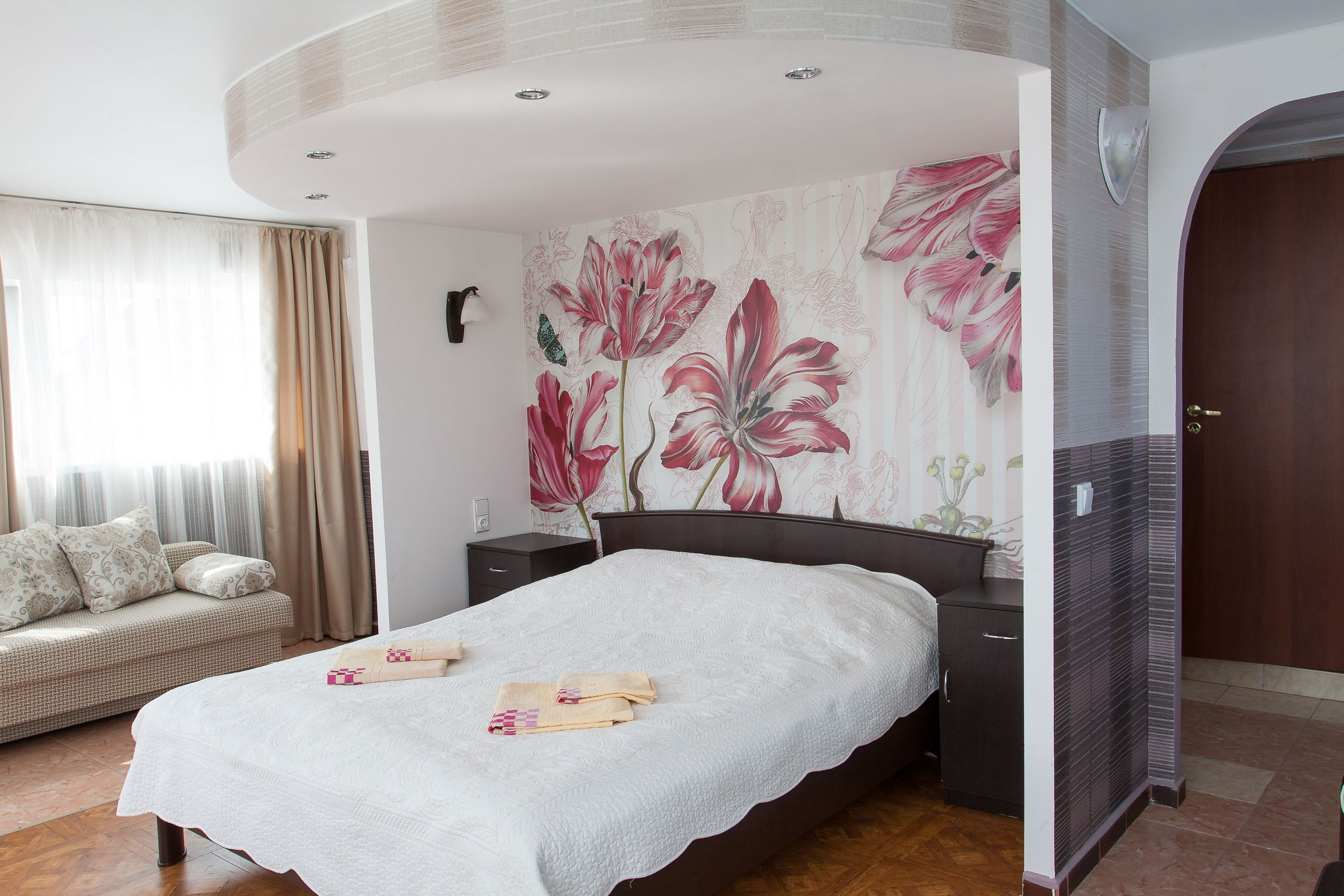 Интерьер гостевого дома Горница, двуспальная кровать и прикроватные тумбы в светлых тонах.