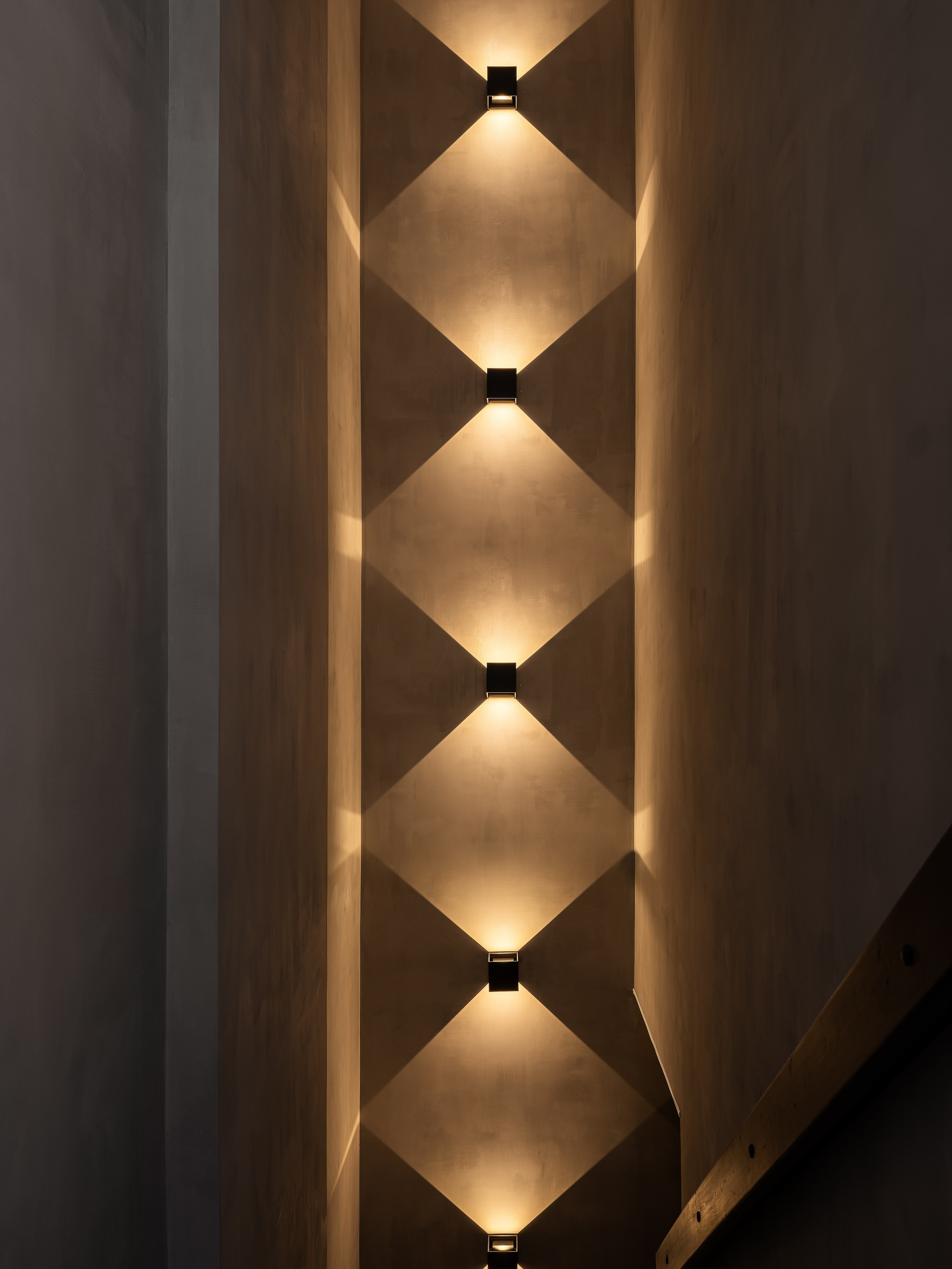 Эффектная лестница с серыми стенами и встроенными светильниками, создающими игру света и тени в минималистичном интерьере. Автор проекта дизайнер Екатерина Мищенко, фотограф Сергей Денисенко, стильный современный дом.