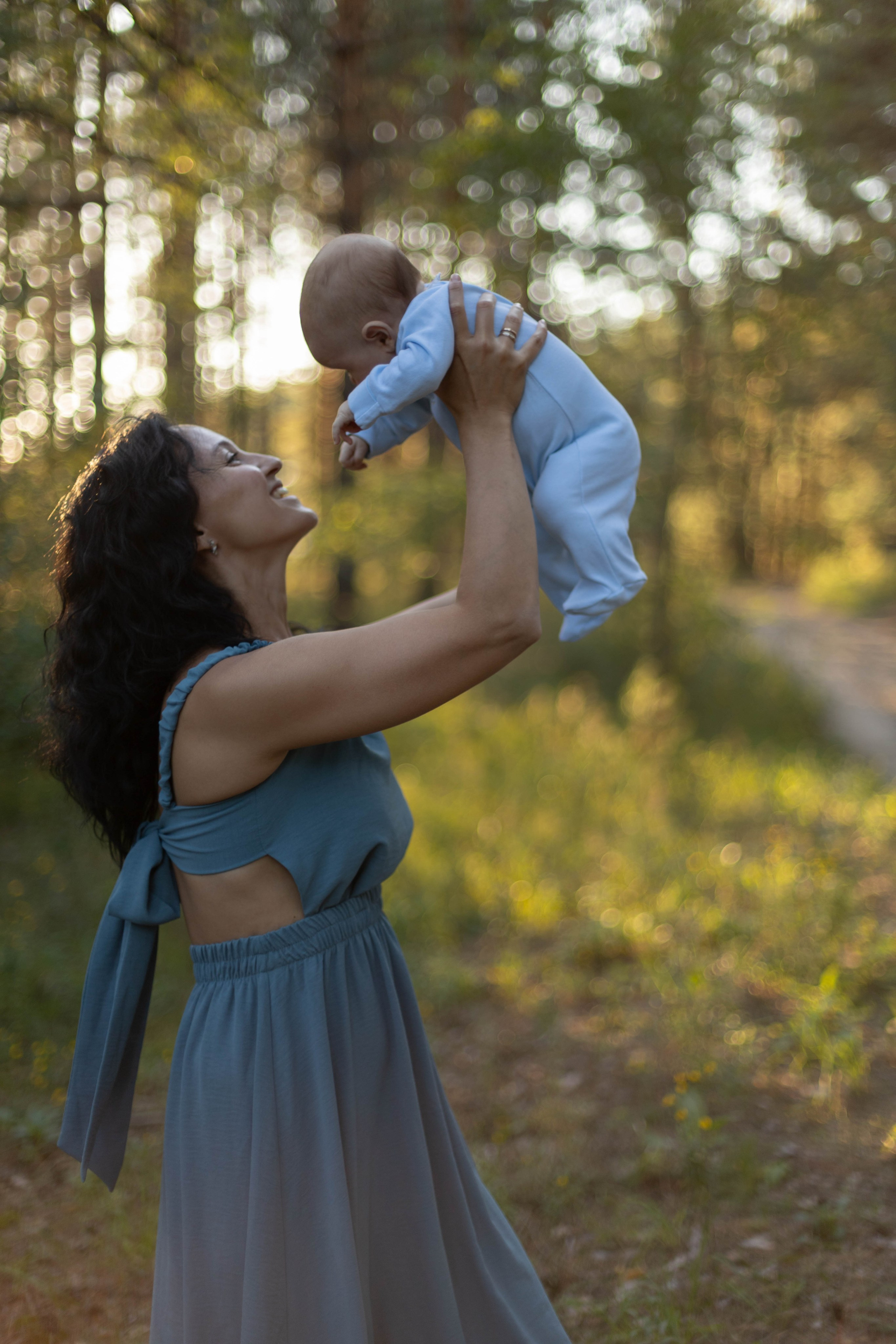 Мама держит ребенка на вытянутых руках, Семейная фотосессия мама, папа и два сына в сосновом лесу летом