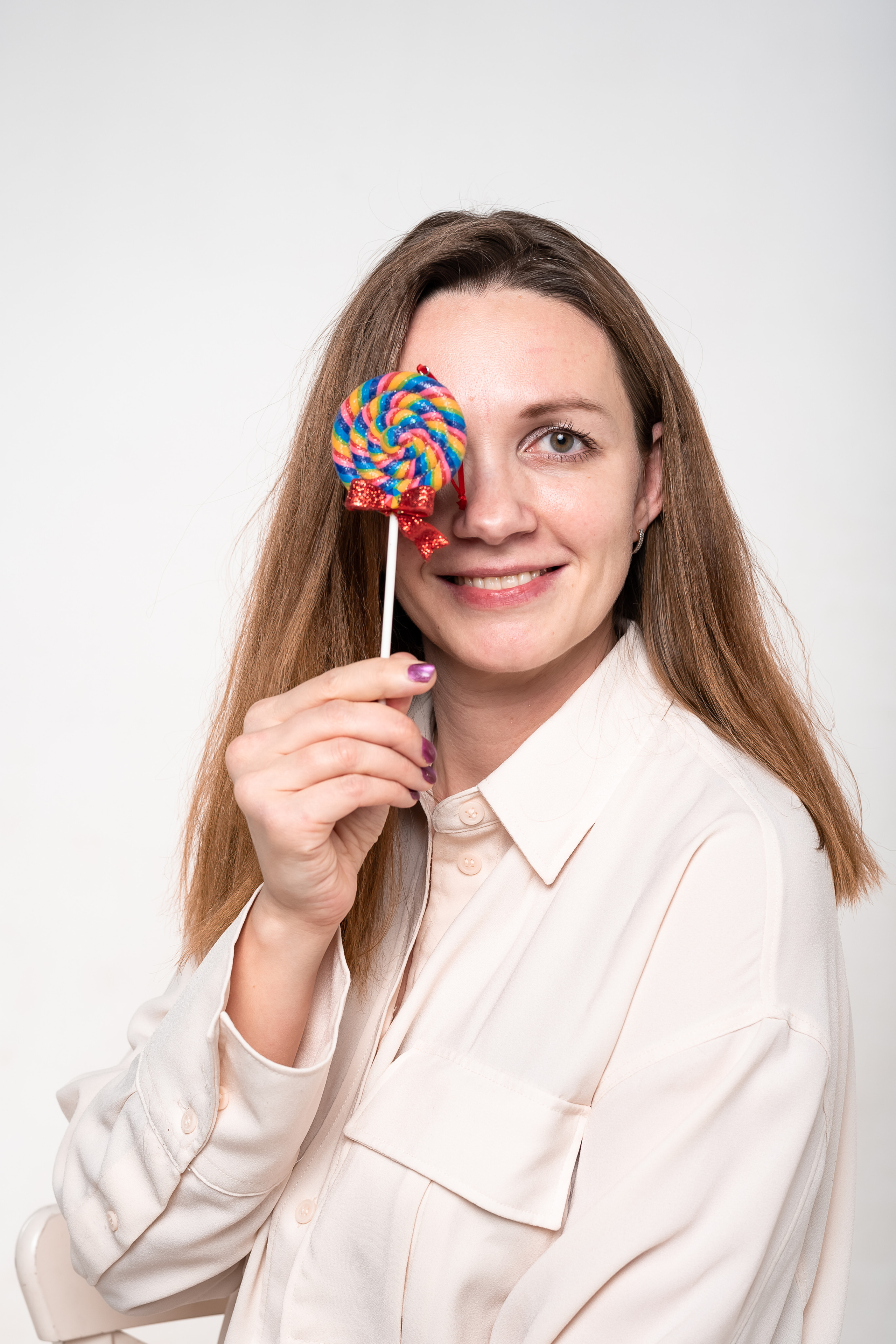 фото девушки прикрывающий один глаз карамельной конфетой 