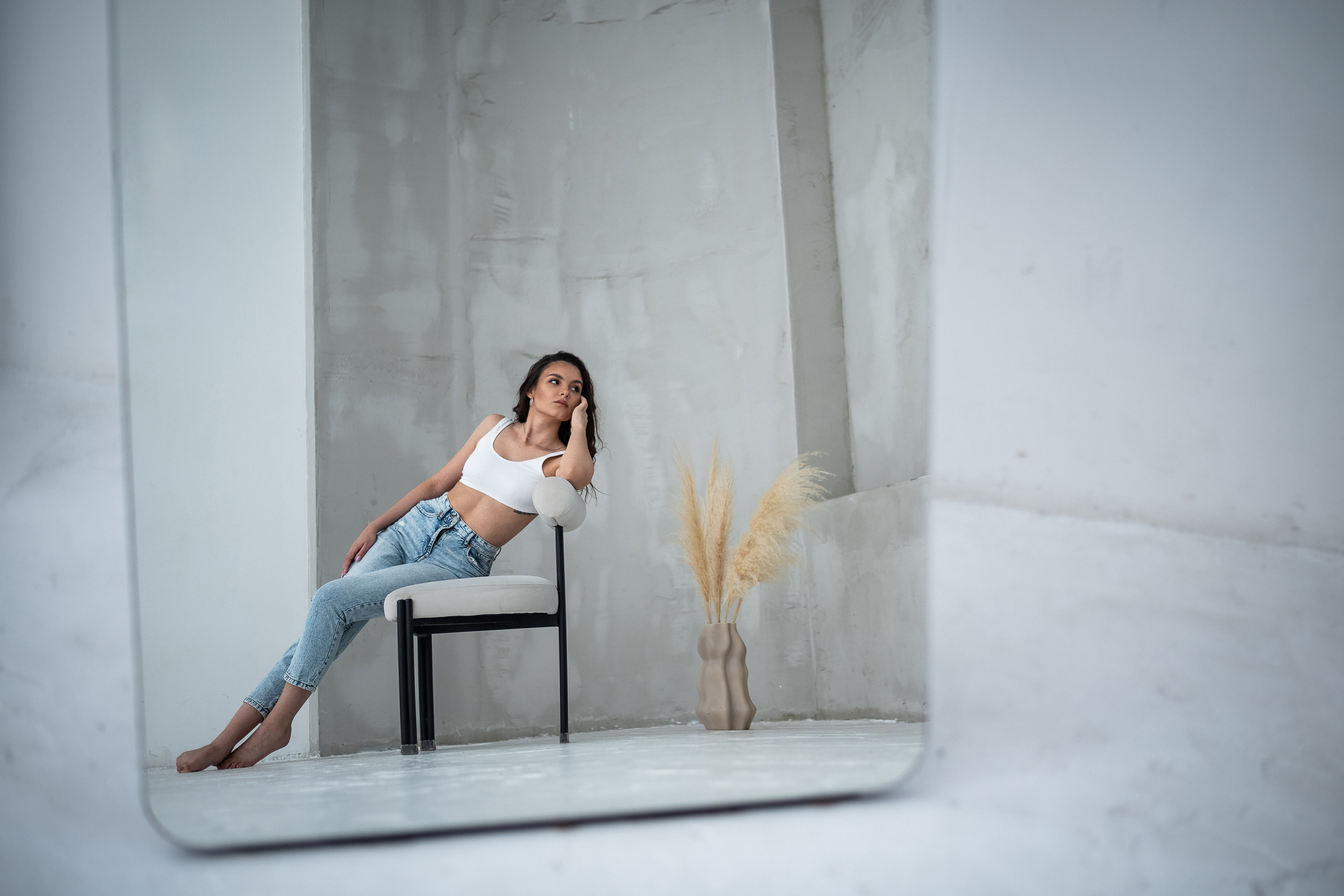 отражение девушки на стуле и вазой с сухостоем